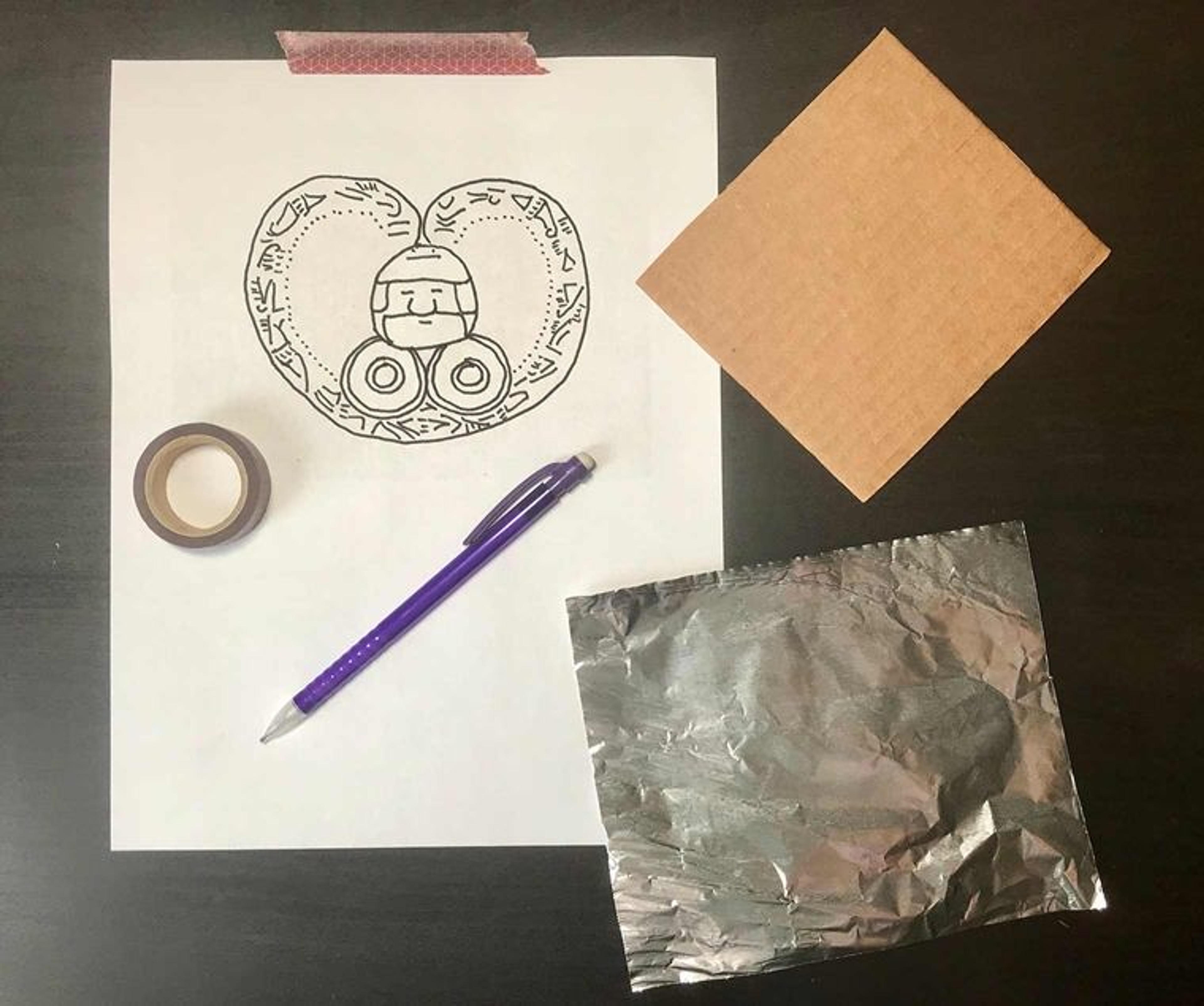 crafting materials to make your own ornament: a drawing on a pieces of paper, tape, cardboard, a pen, and a small rectangle of tin foil.