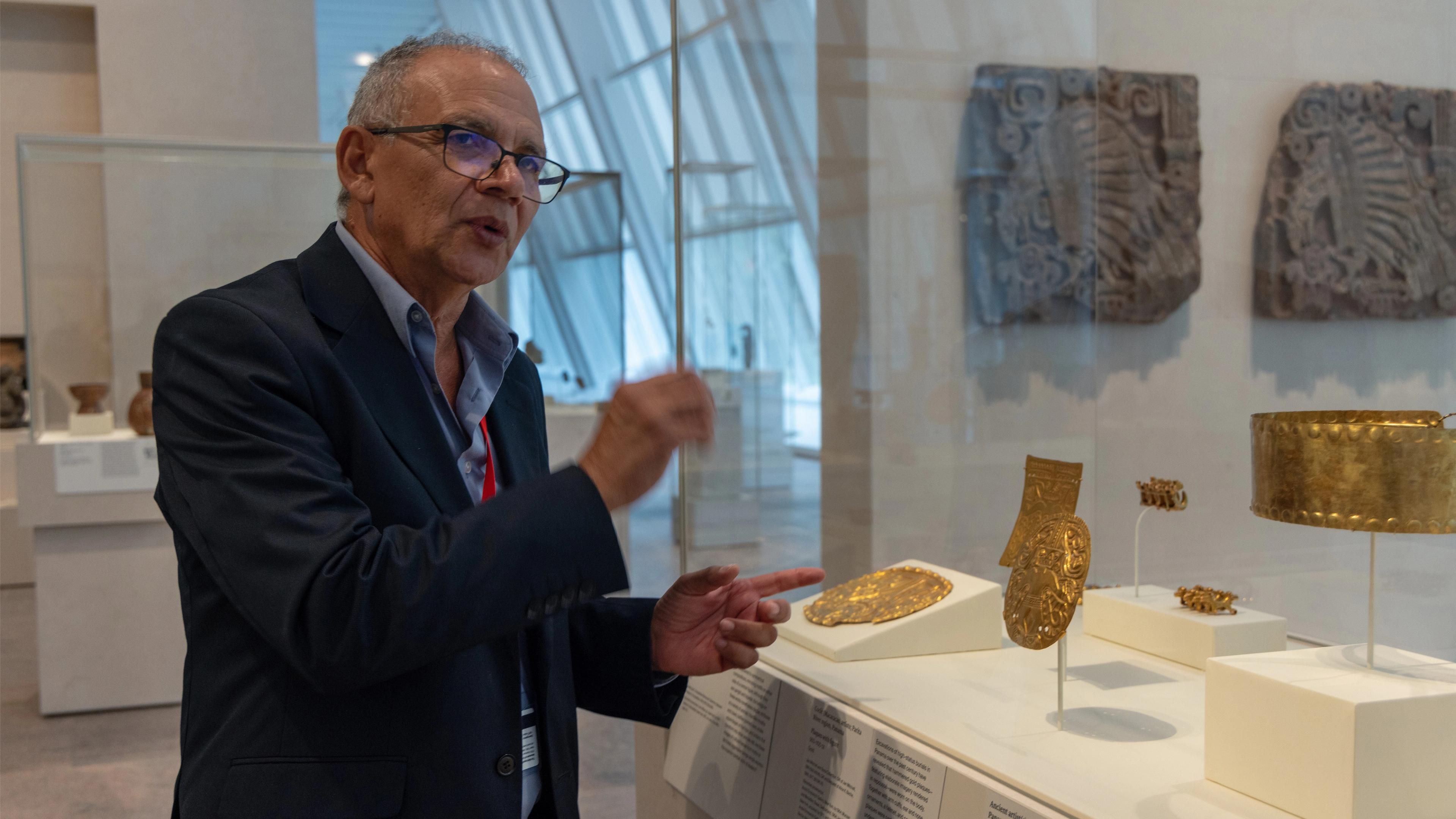 Francisco Corrales Ulloa talking in front of a gold plaque in the Arts of the Ancient Americas galleries