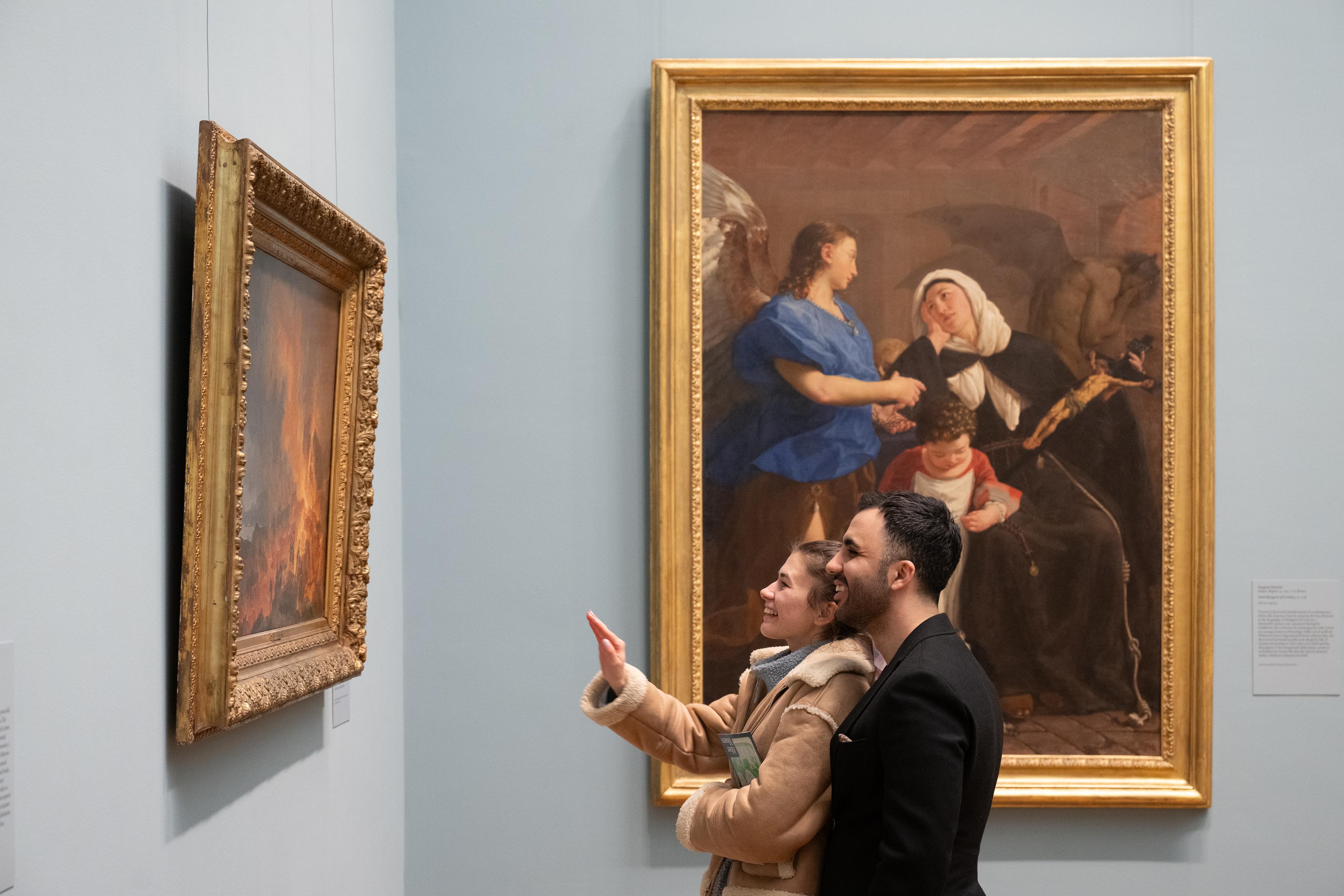 a couple looks at a work of art in The Met's European Paintings galleries.