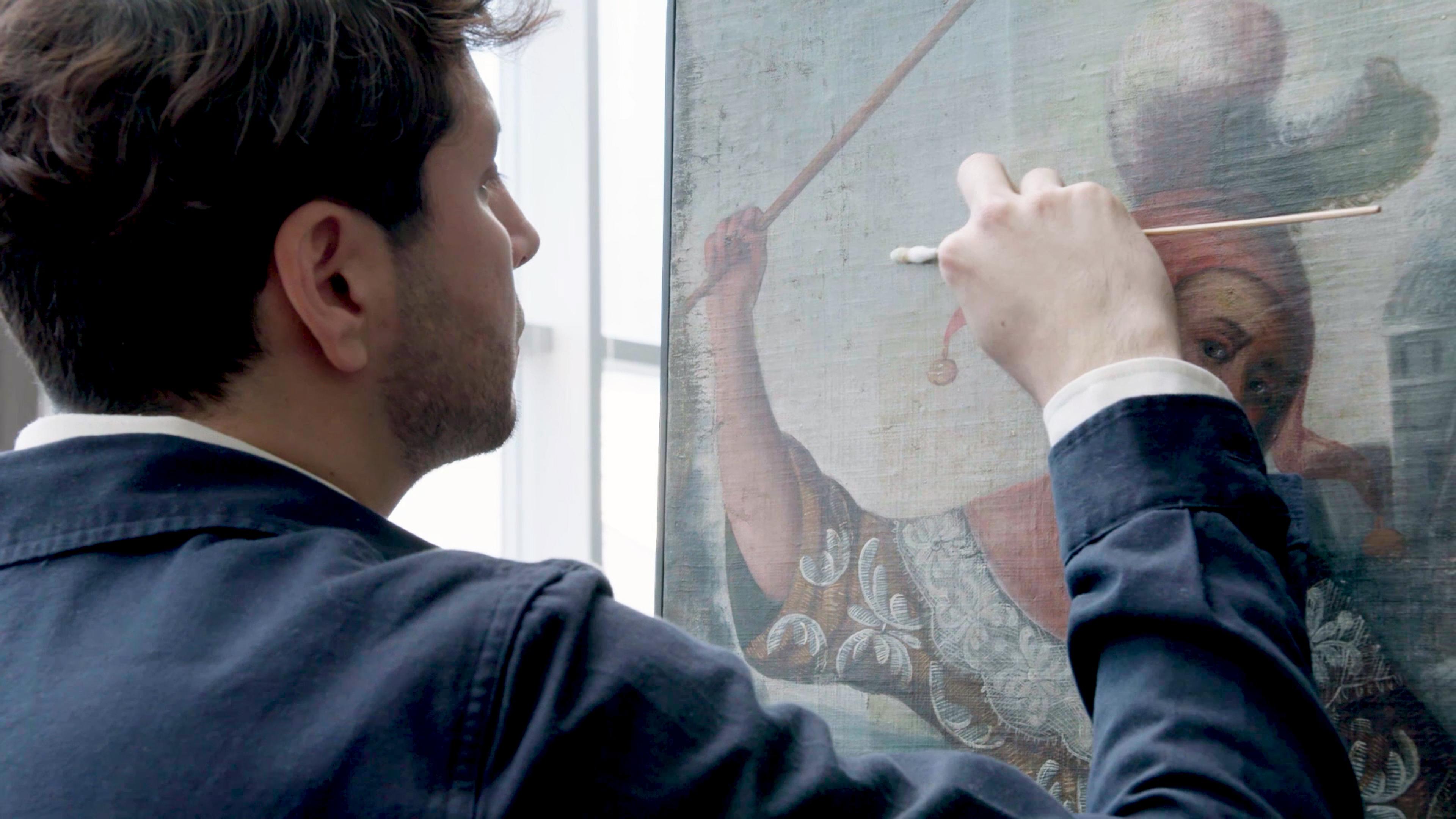 A conservator at work on a painting.