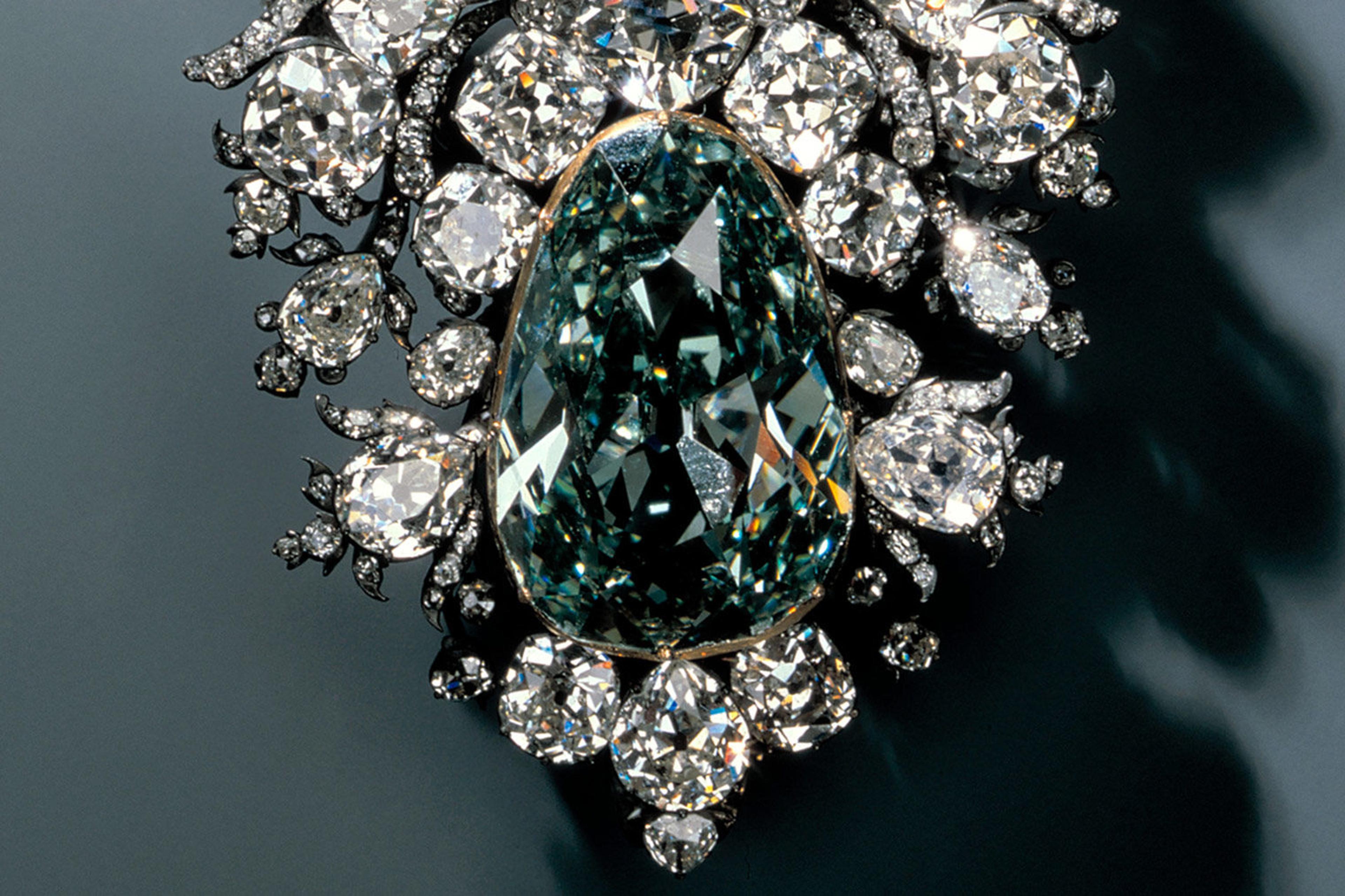 A massive green diamond, cut in a pear shape and set in an ornate silver and diamond ornament