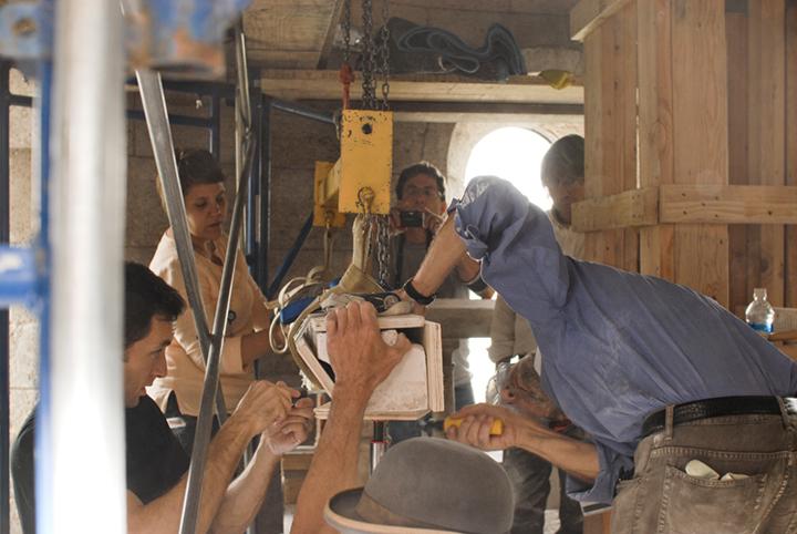 Conservators working to free a lintel from the structure. The stone is protected from rigging straps and chains with wooden planks.