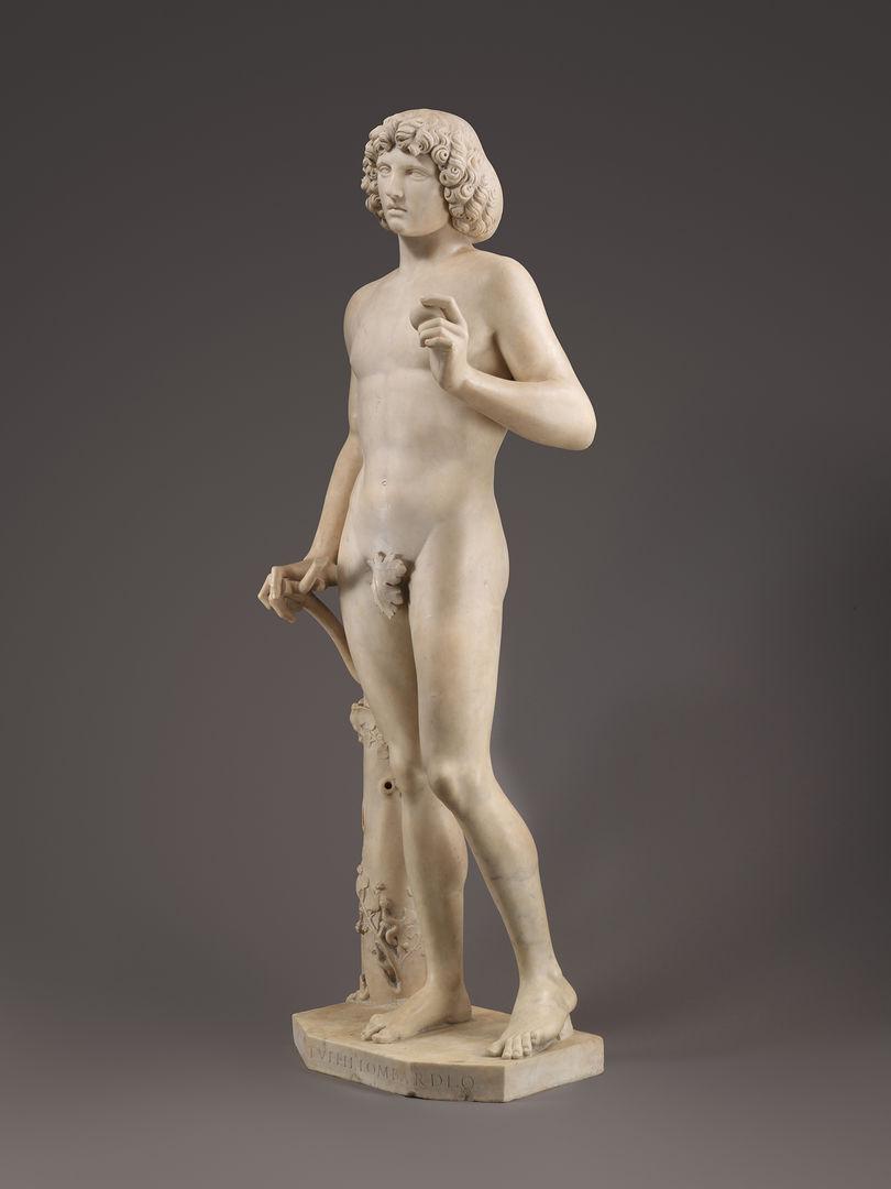 Marble statue of Adam by Tullio Lombardo. His figure casts a shadow against the gray background.