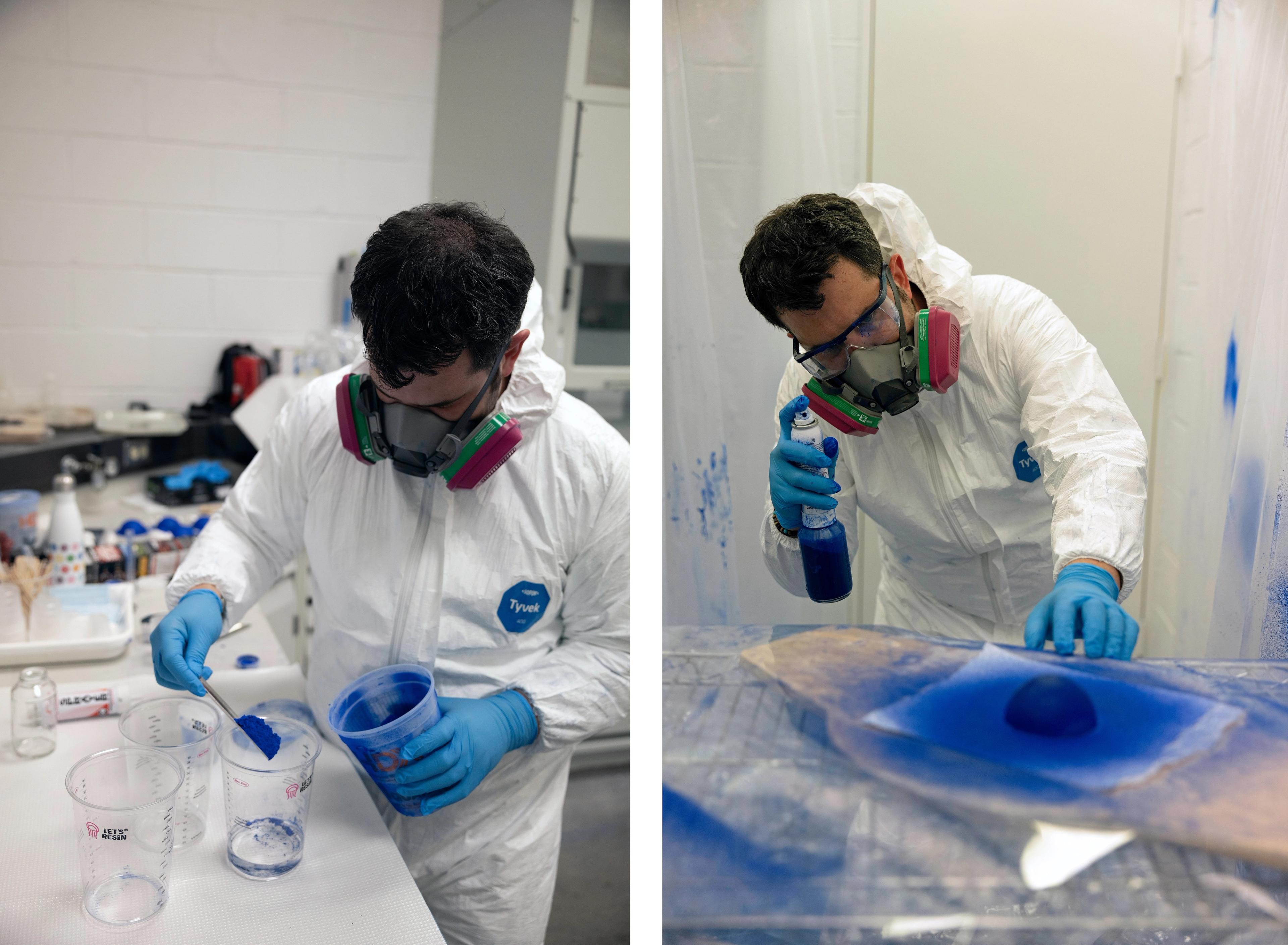 Person in a mask and white suit applying blue paint to a dome.