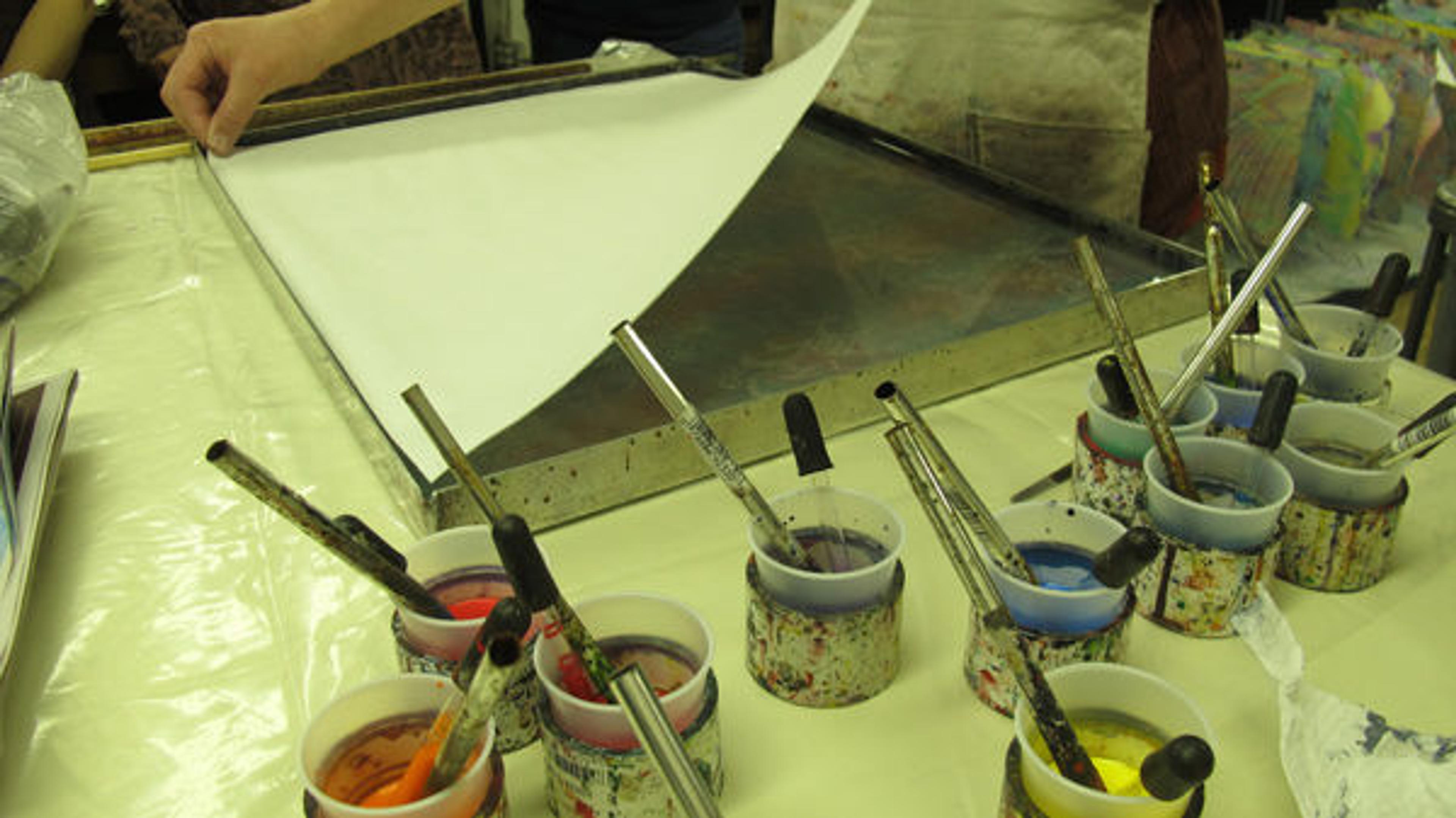Carefully laying down the prepared alum-sized paper to transfer the marbled dyes