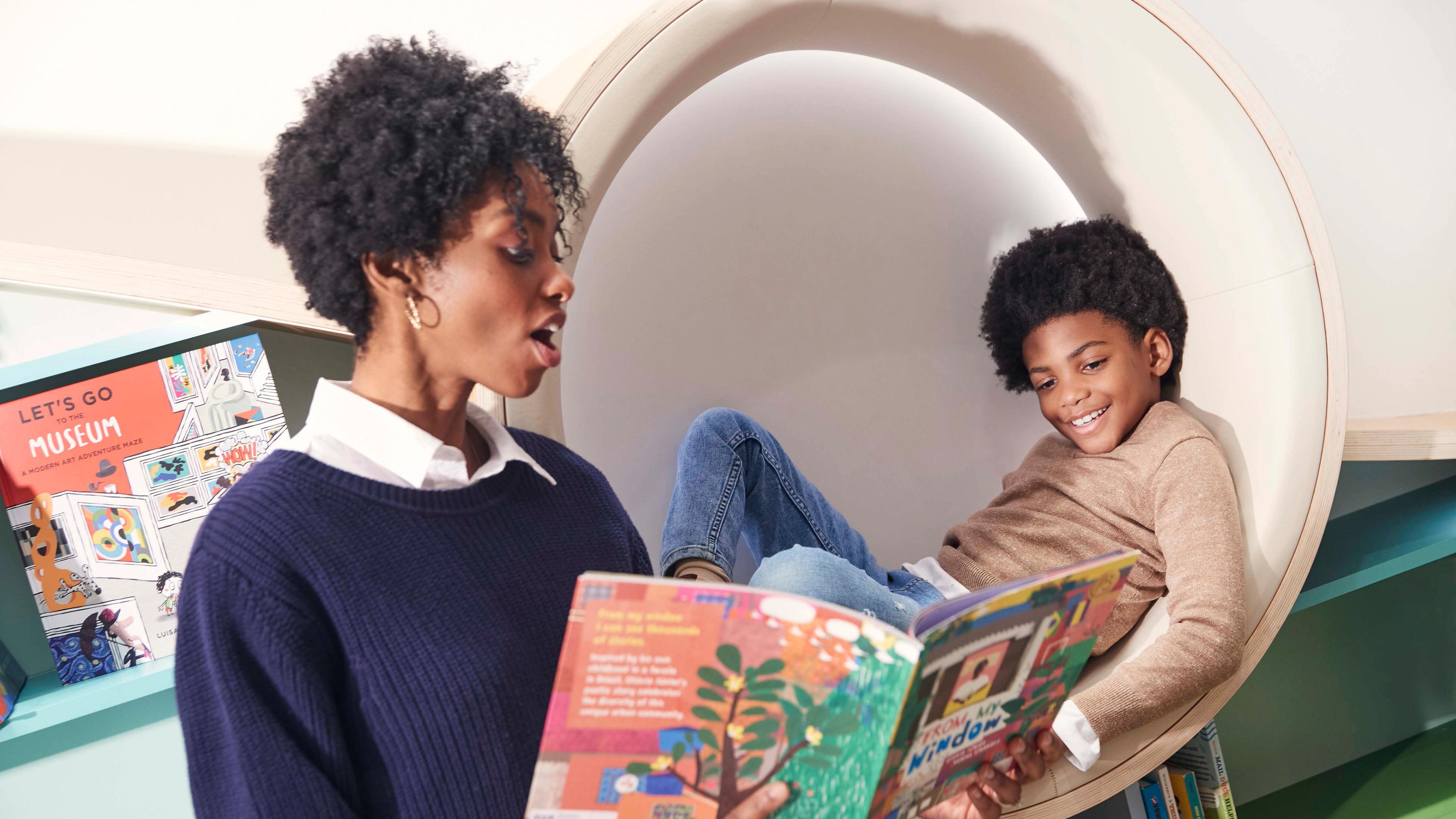 A mother reads a book to her son in the 81st Street Studio playspace at The Met Fifth Avenue.