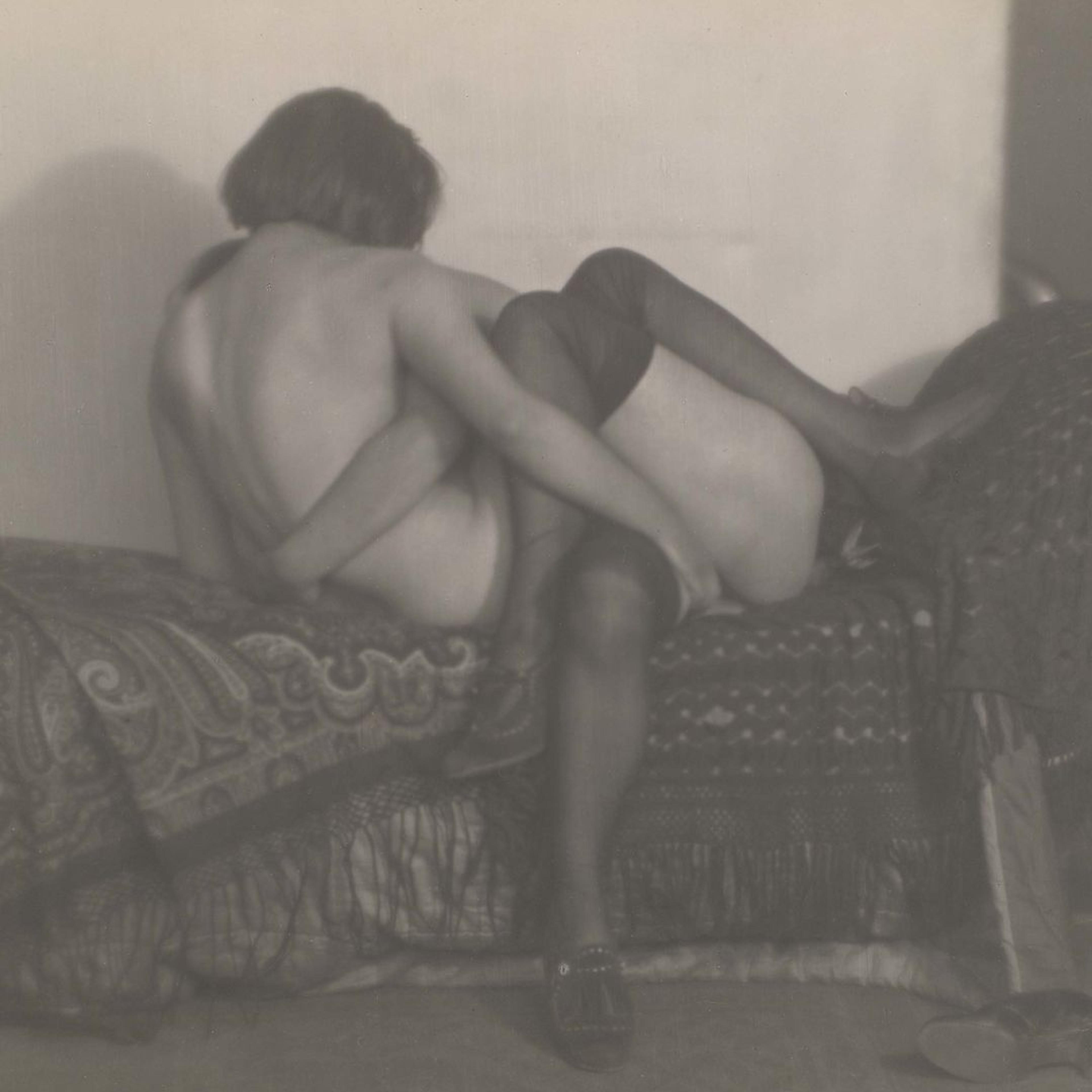 A black and white photograph of two nude women in a loving embrace.