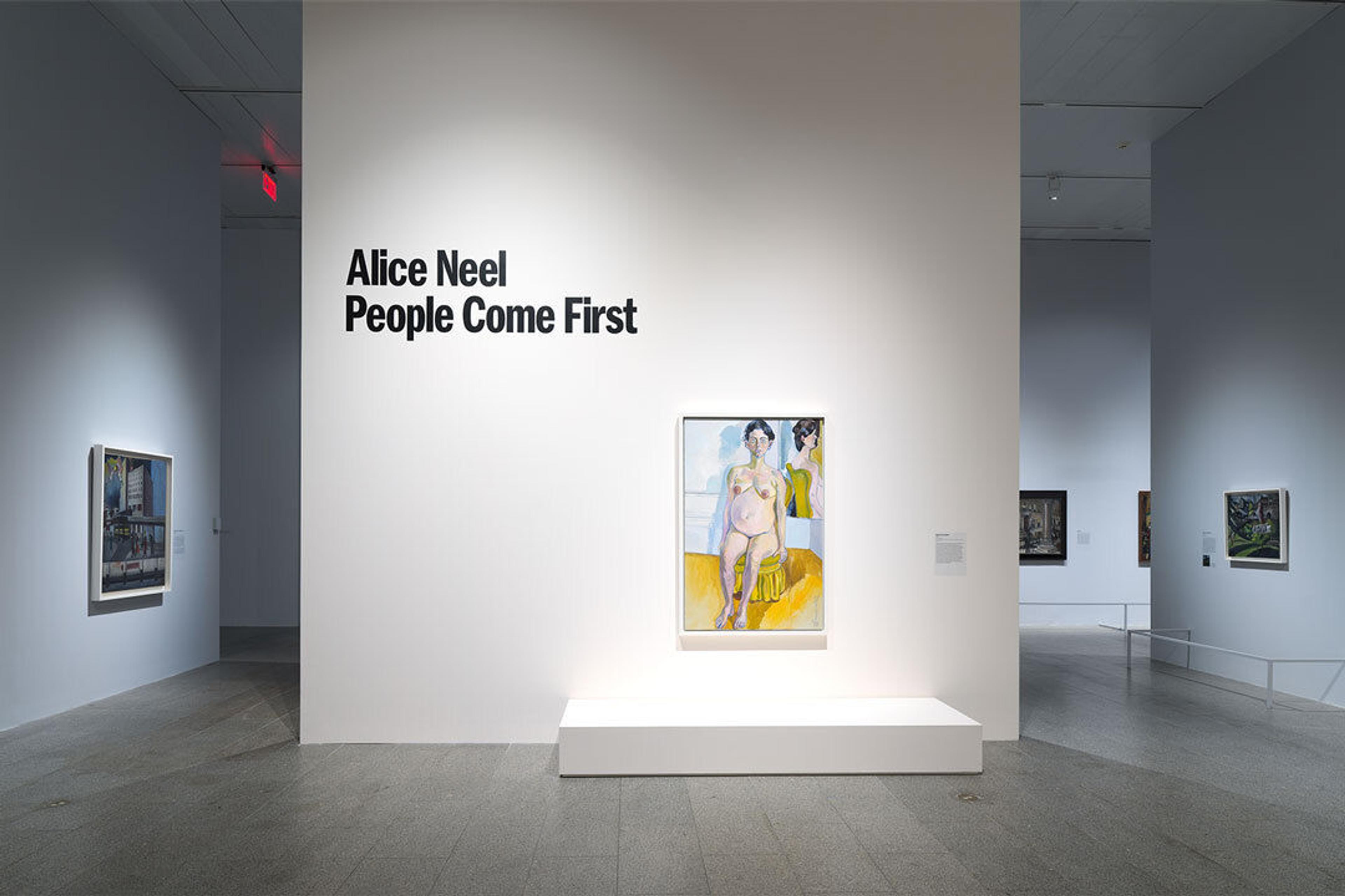 A white-walled gallery with several paintings hung on the walls