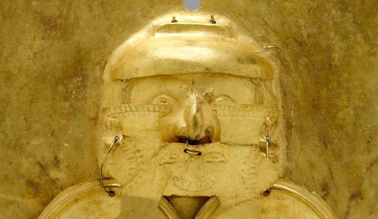 A detail of a face on a heart-shaped gold pendant from Colombia.