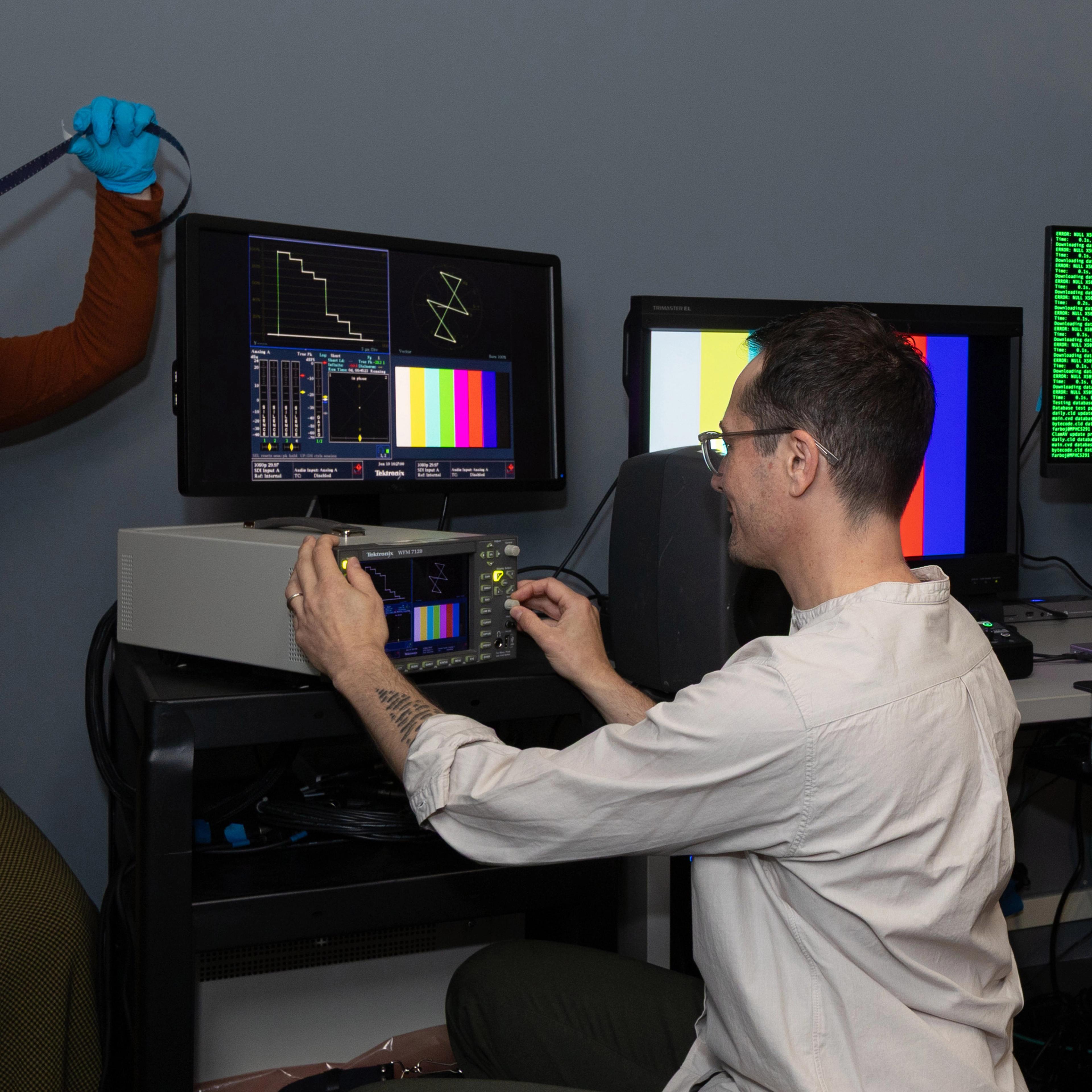 A person working in a media lab operating electronic equipment.