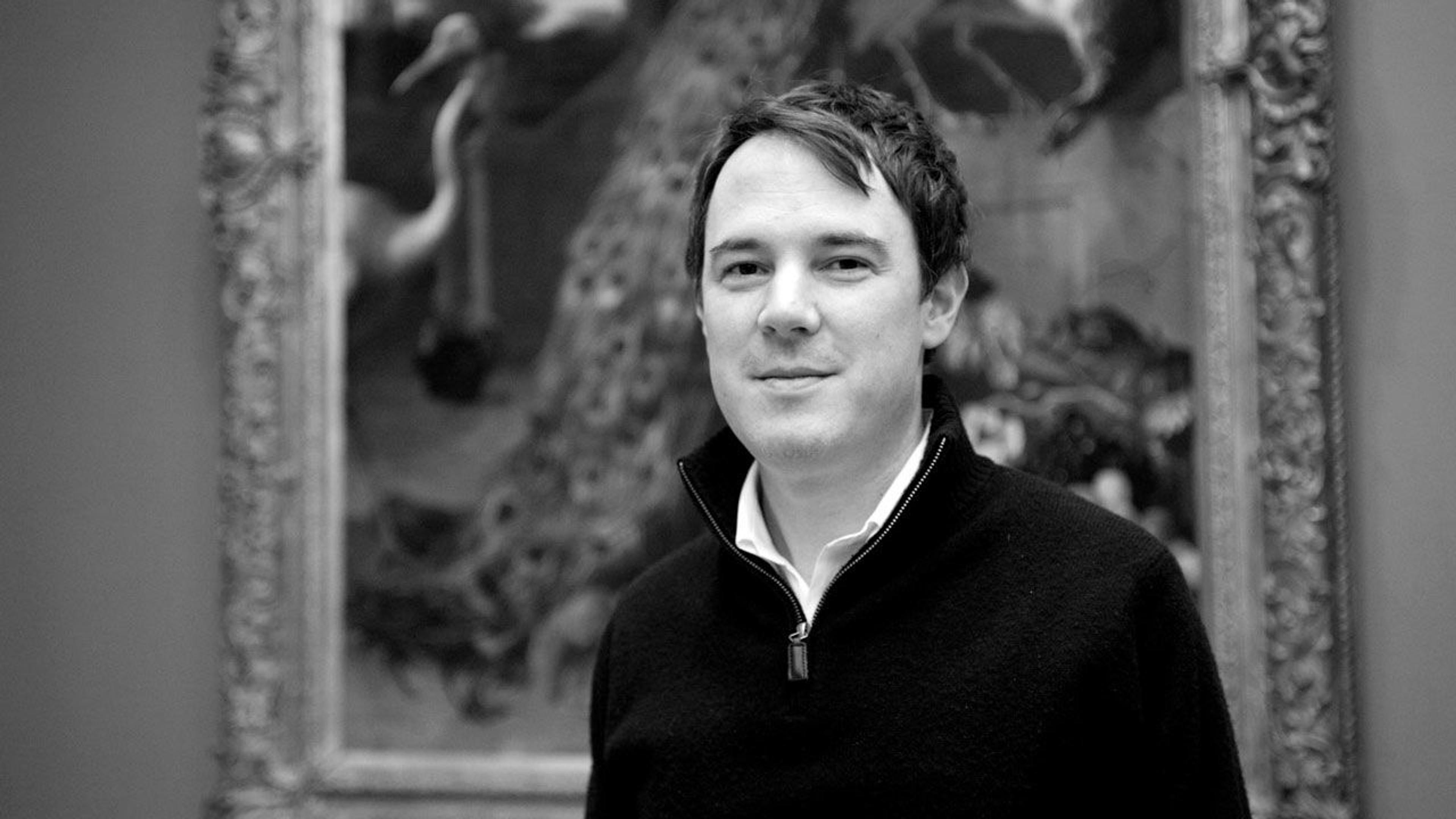 Black and white photograph of Dale Tucker standing in front of a painting in The Met galleries