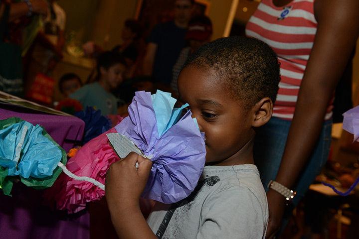 Boy smelling a paper flower during the Senses of Springtime festival