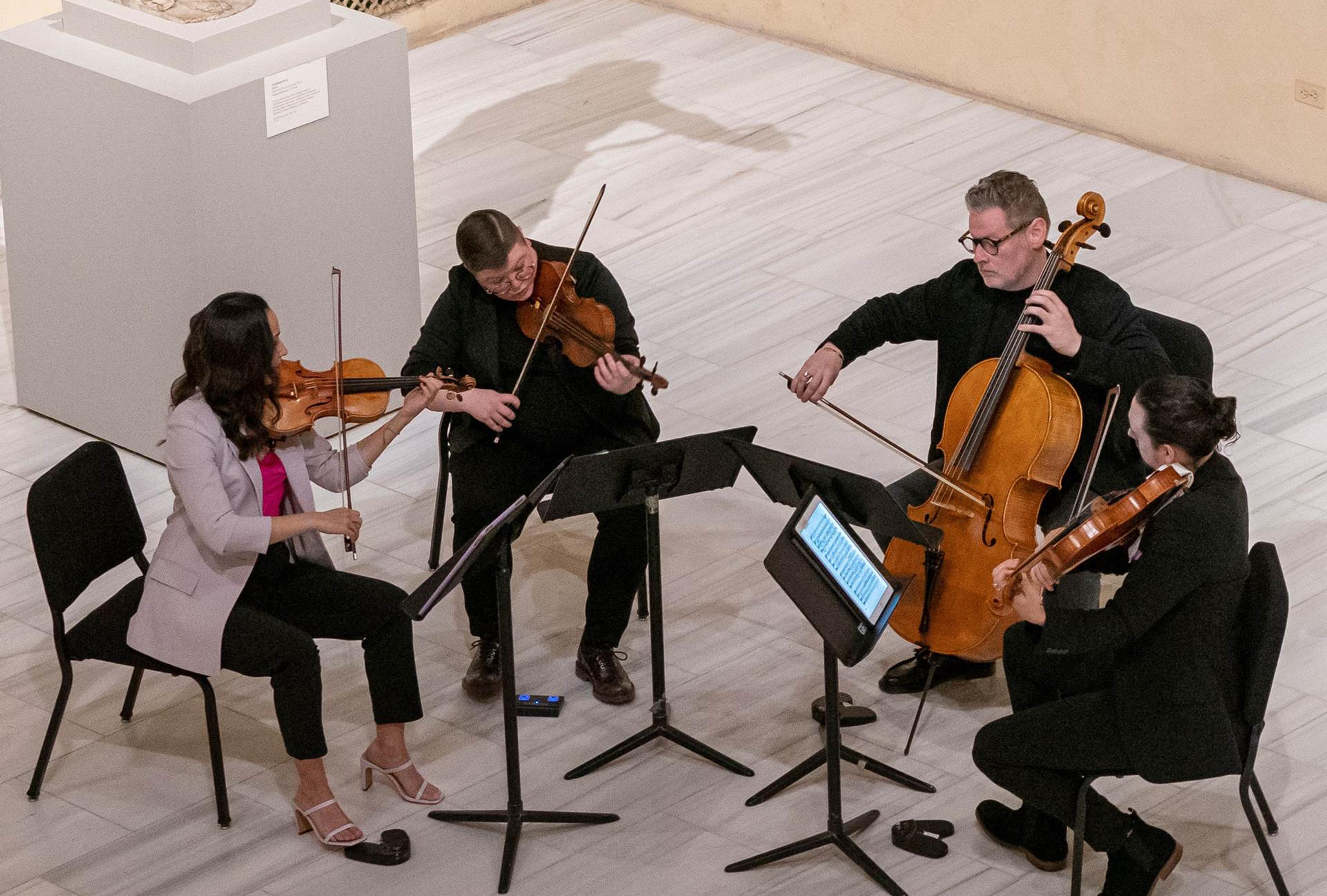 A quartet plays seated in a Met Gallery. 