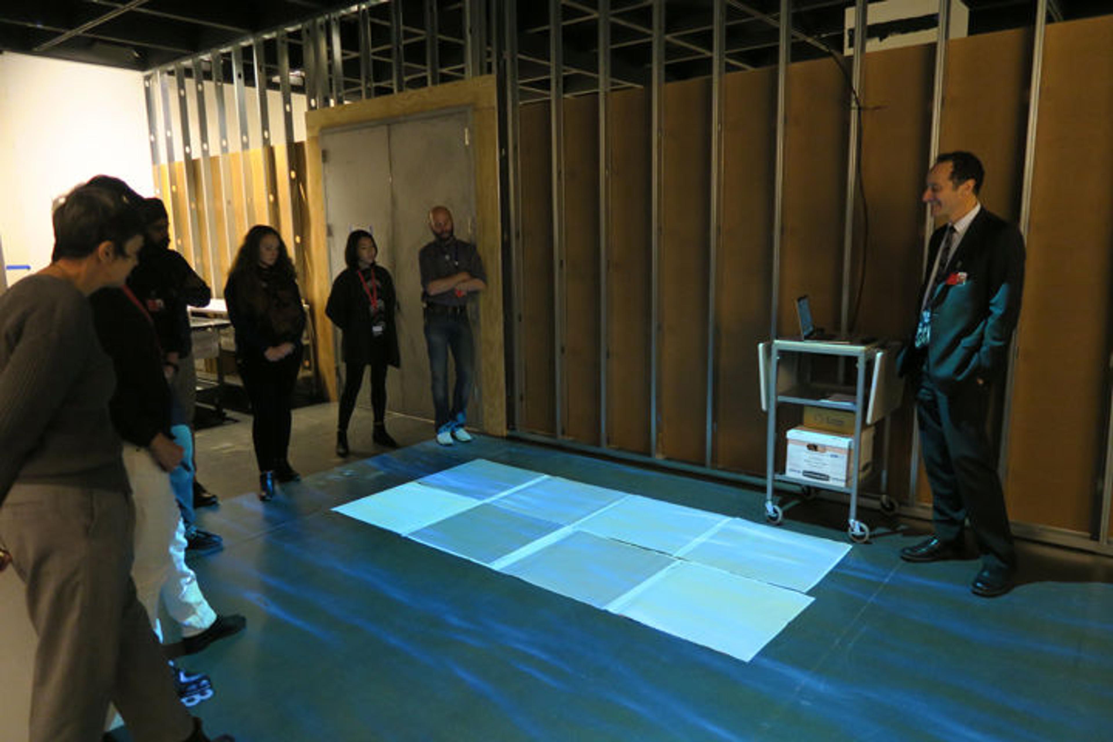 A group of Met staff members view a digital projection in an empty exhibition gallery