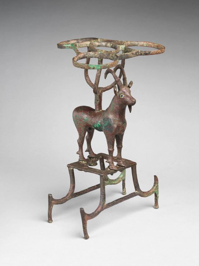 Copper stand comprised of an ibex with supports for vessels on its back and below its feet. The sculpture shows some green oxidation.