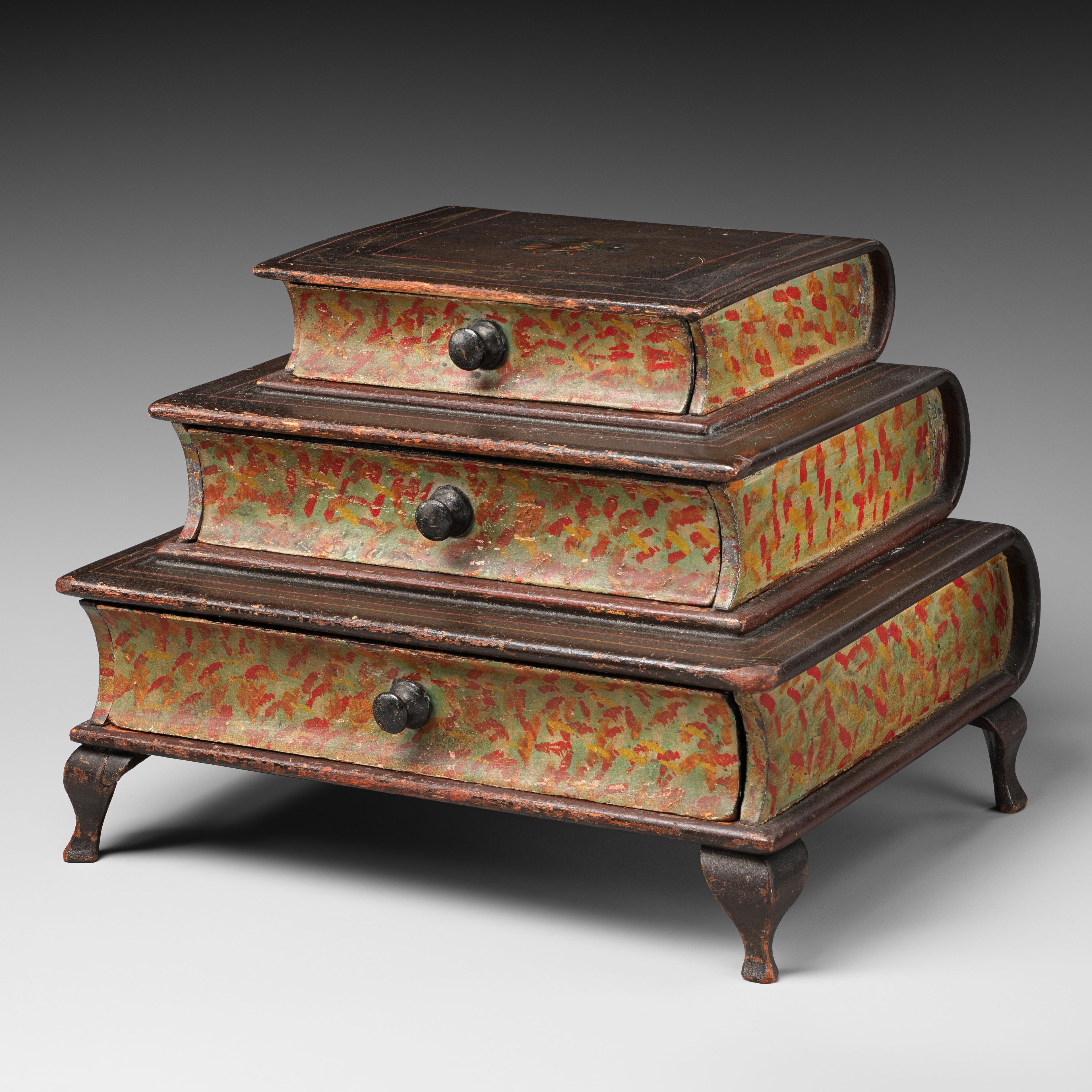 A set of three antique, graduated, stackable wooden boxes, each with a curved lid, painted in a distressed red with faint foliage motifs, featuring a central metal pull handle, resting on small, stylized feet.