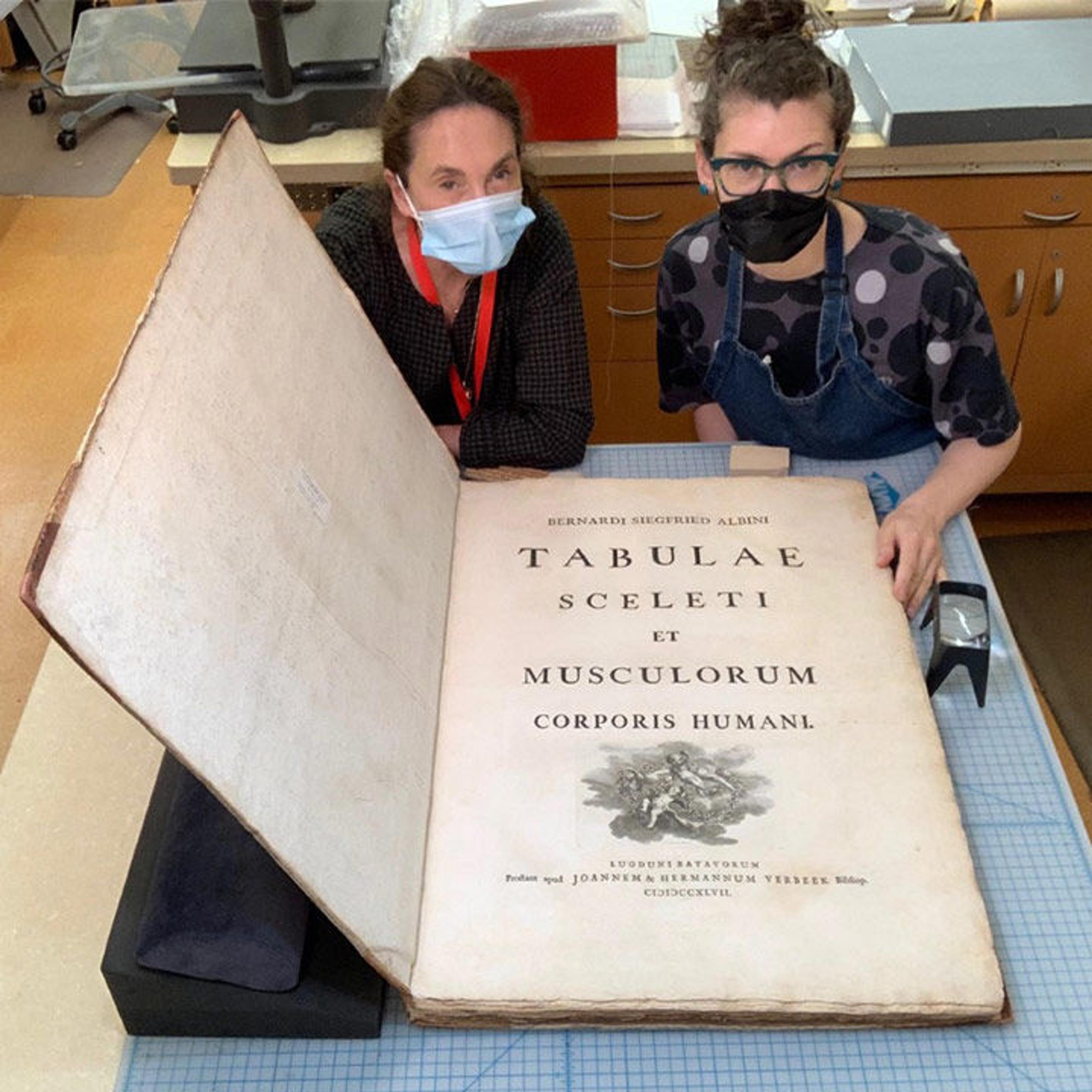 Books conservation staff with large book