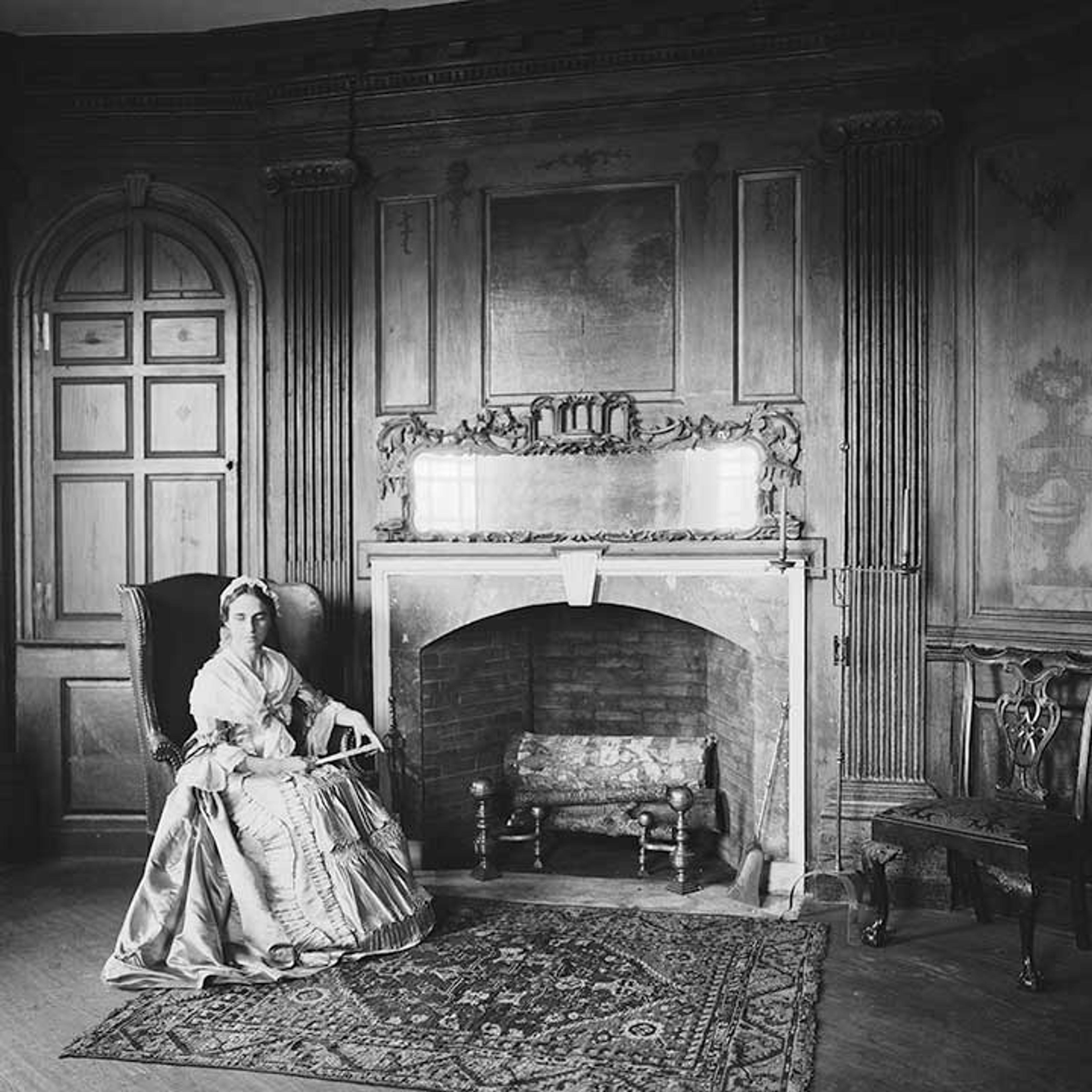 Black-and-white image of an actor in 18th-century period costume sitting in the Marmion Room