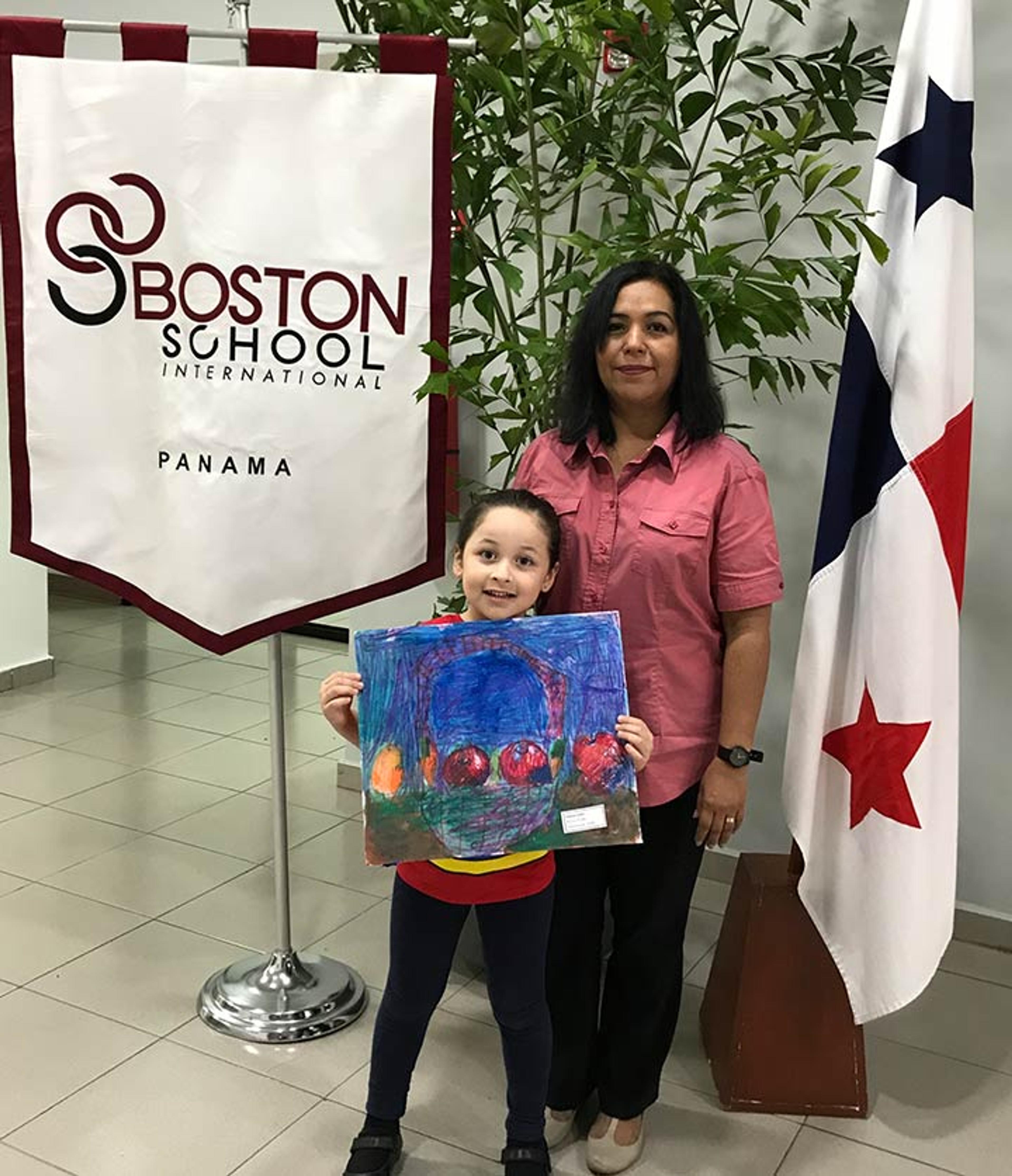 Paula is holding her artwork featured earlier and stands with her art teacher.