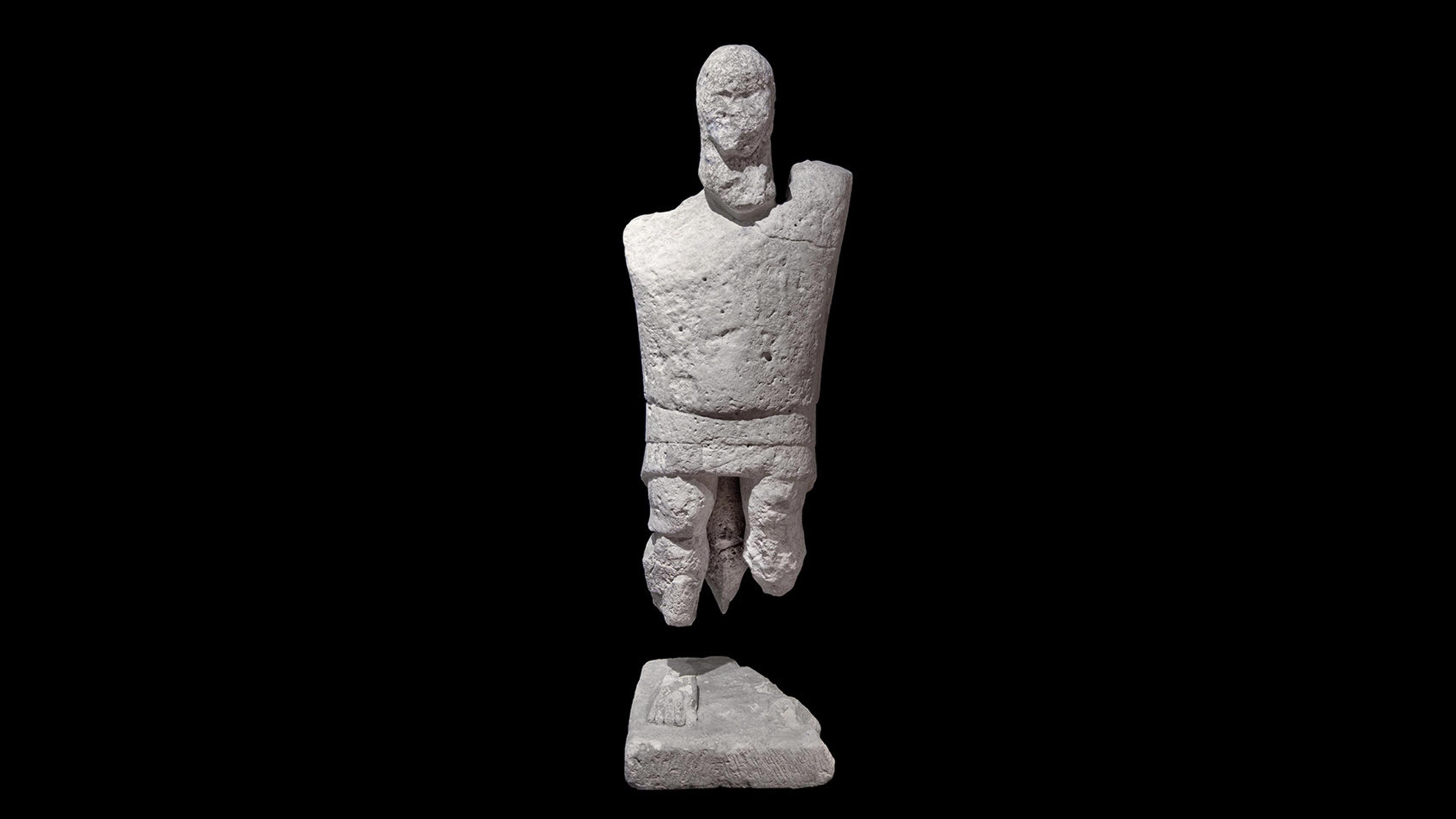 Stone Mannedu statue against a black background