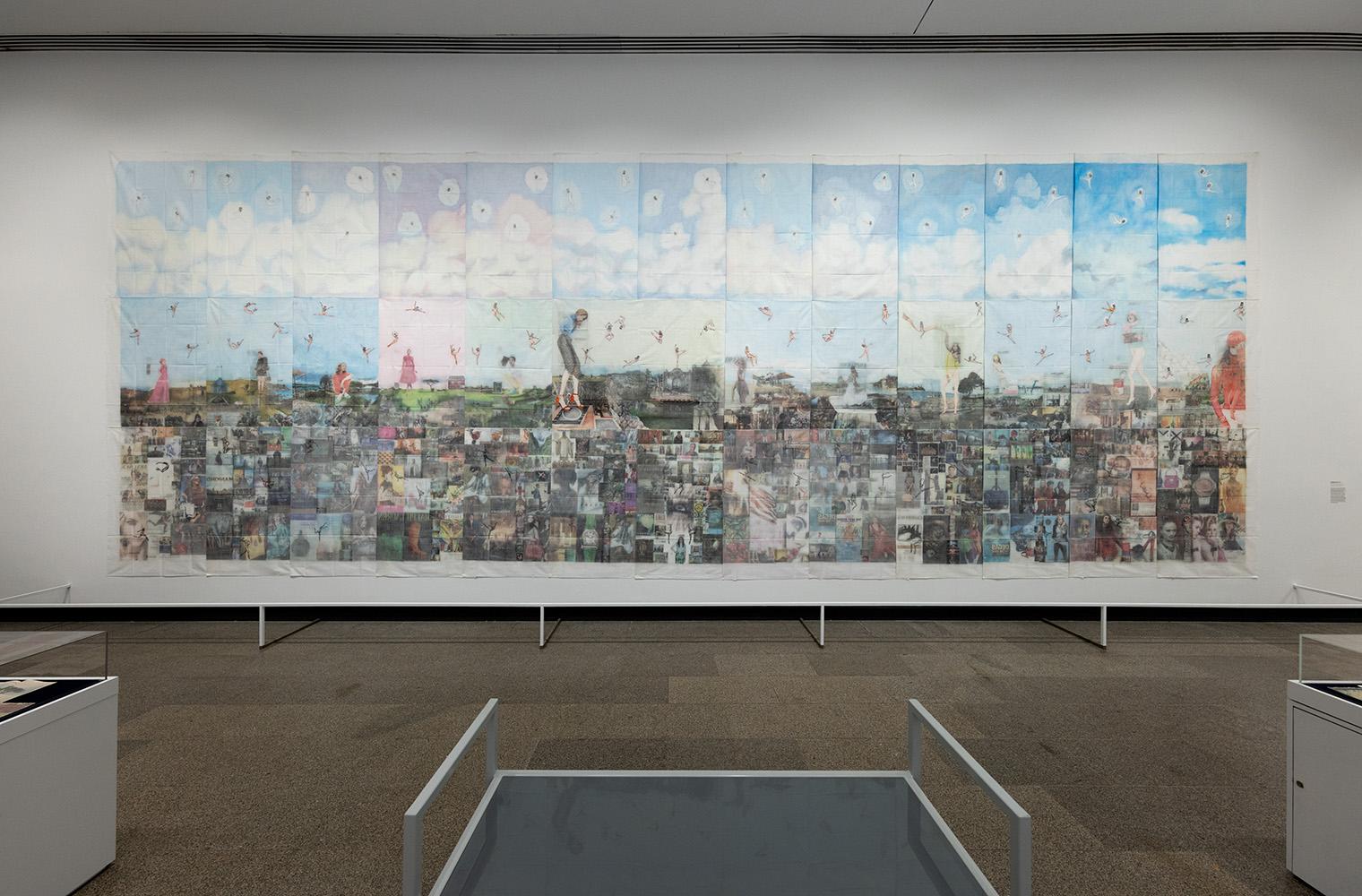 A large collage artwork on a gallery wall, depicting a dreamy sky with clouds and floating figures above a montage of various images, creating a surreal landscape.