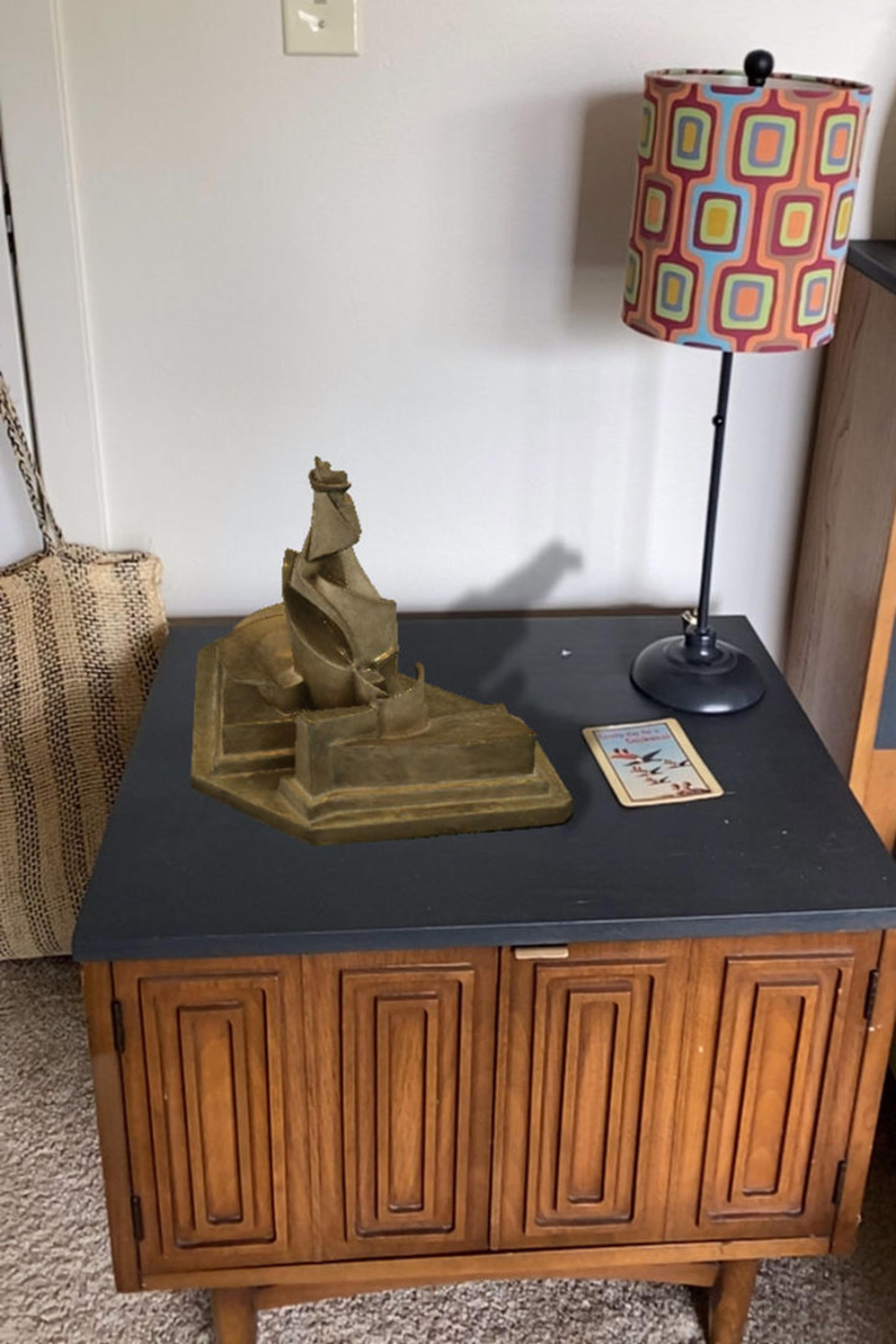An augmented image of Umberto Boccioni’s Development of a Bottle in Space on a side table beside a lamp
