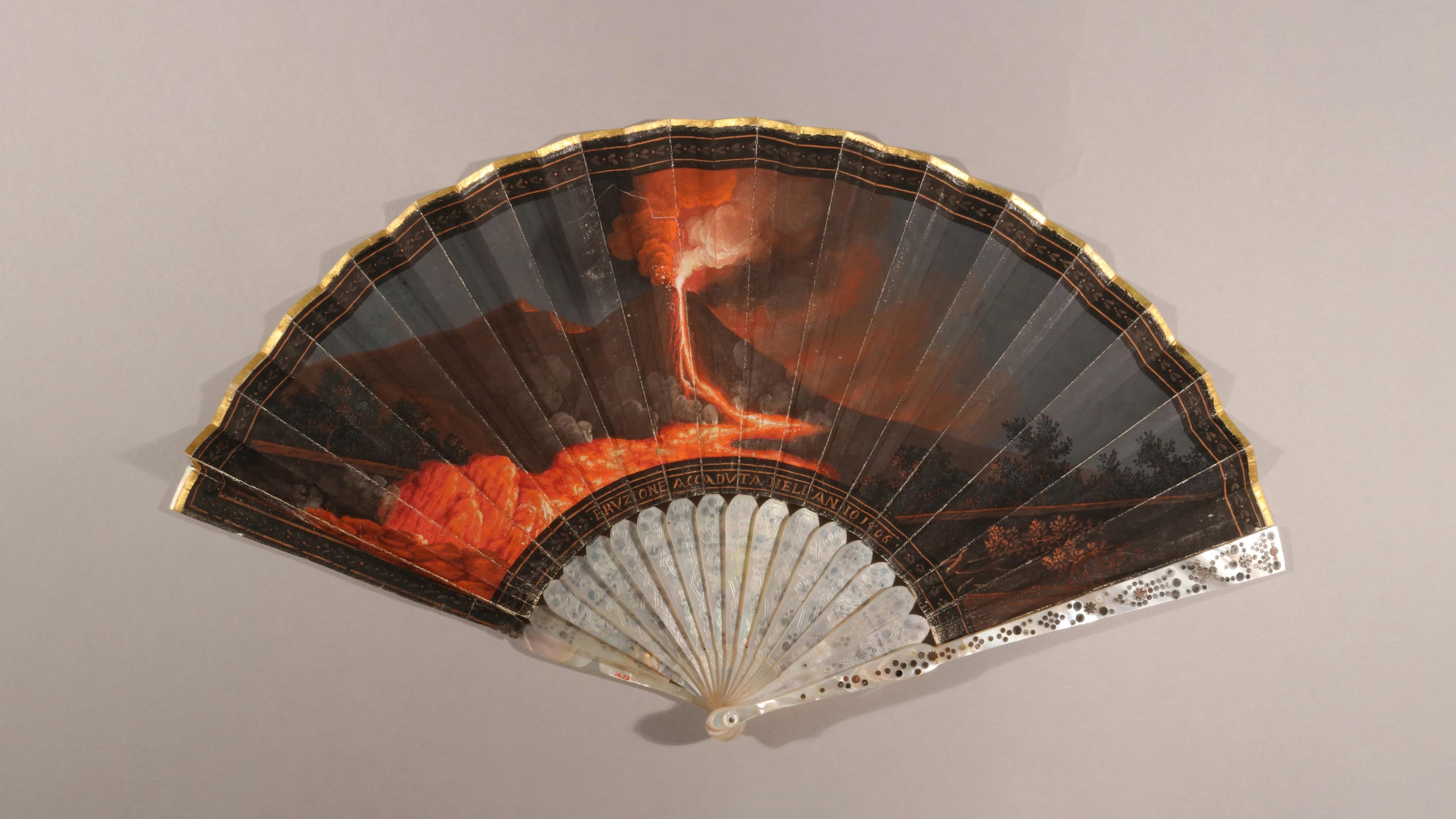 Fan showing a dramatic scene of a volcanic eruption and lava flow.