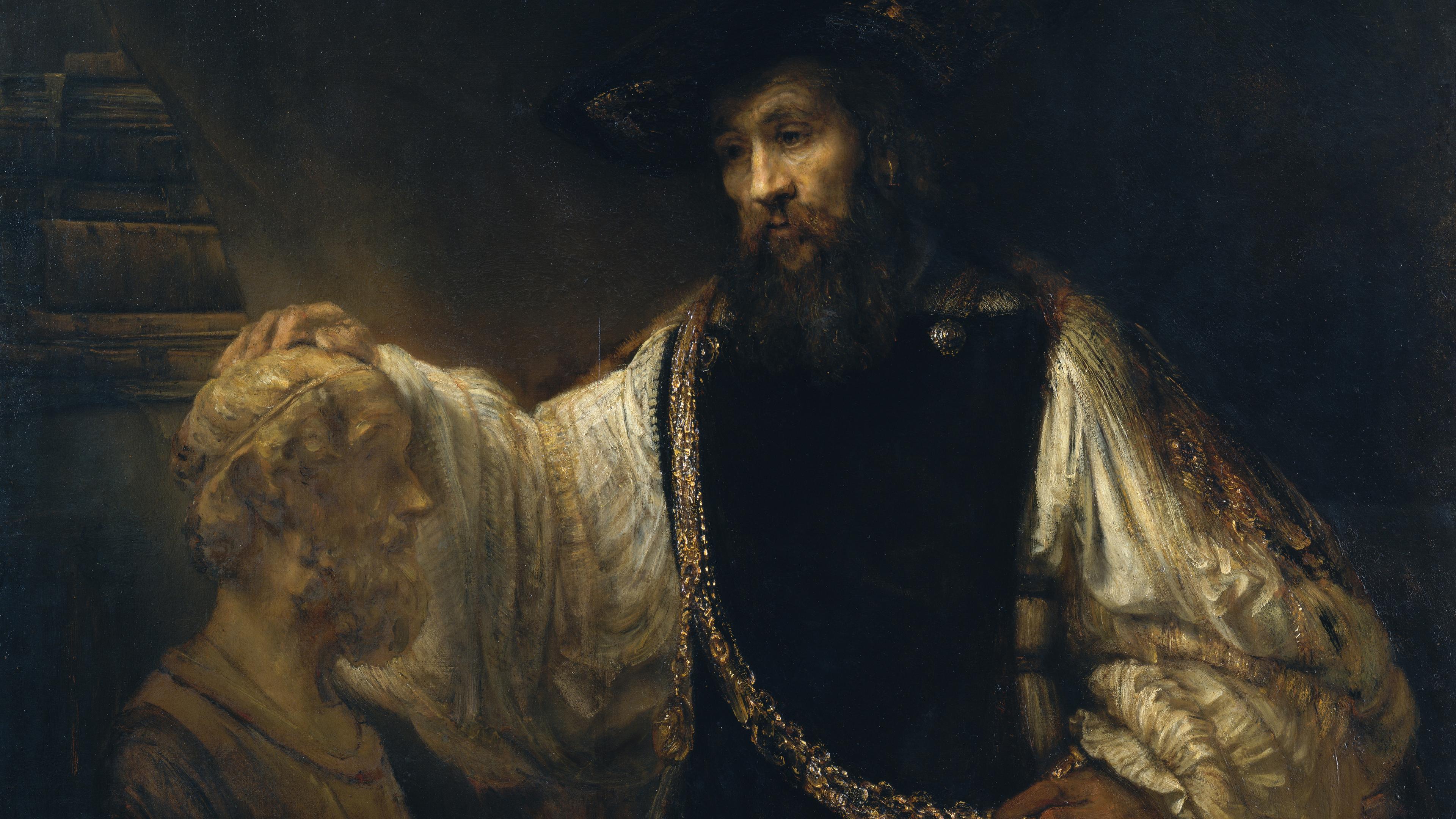 A dark Baroque painting shows a bearded man in a broad hat and ornate robes resting a hand on an older seated figure’s head