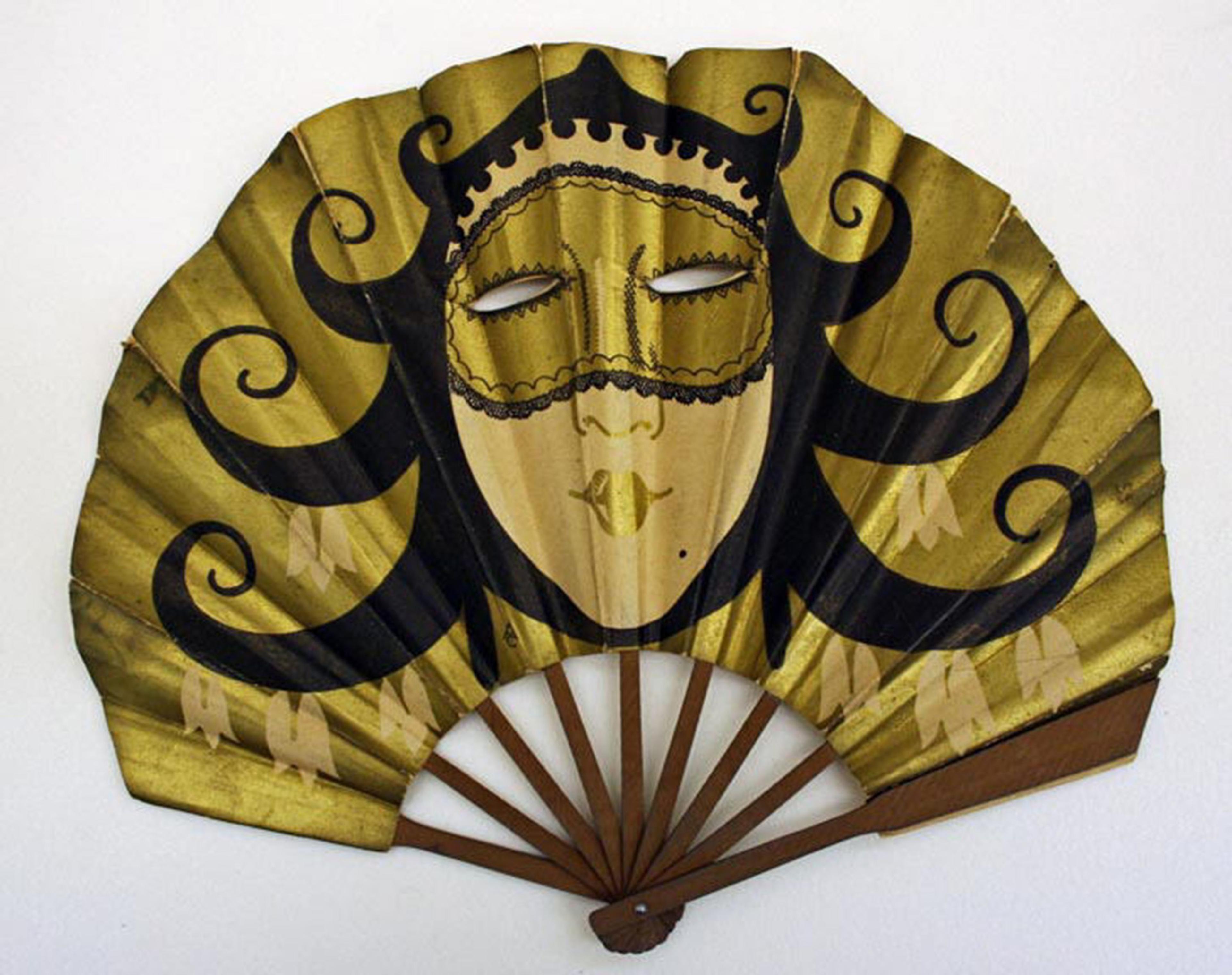 A decorative fan featuring a stylized woman's face with a golden mask and flowing black hair, set against a golden background.