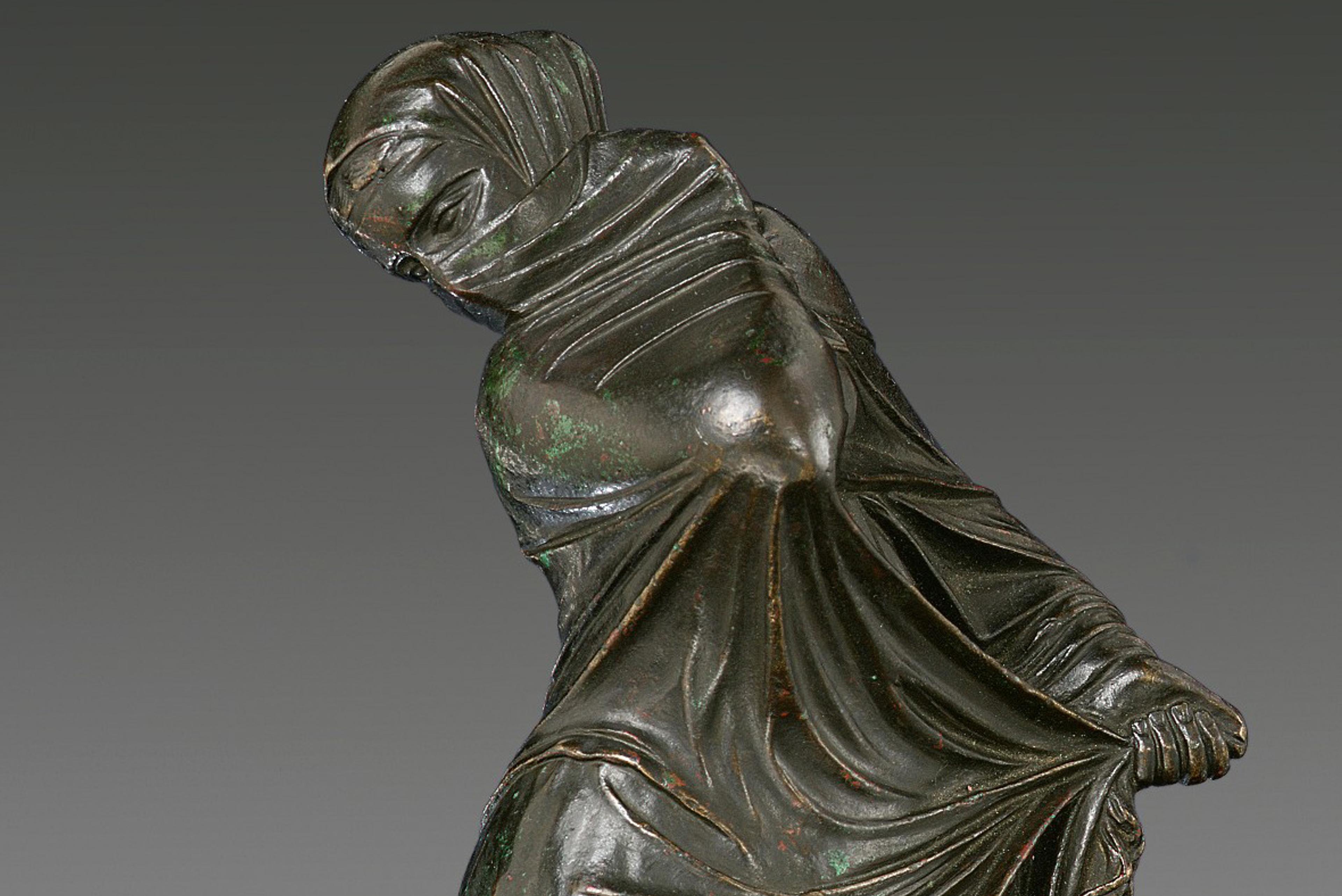 Bronze statuette of a veiled and masked female dancer.