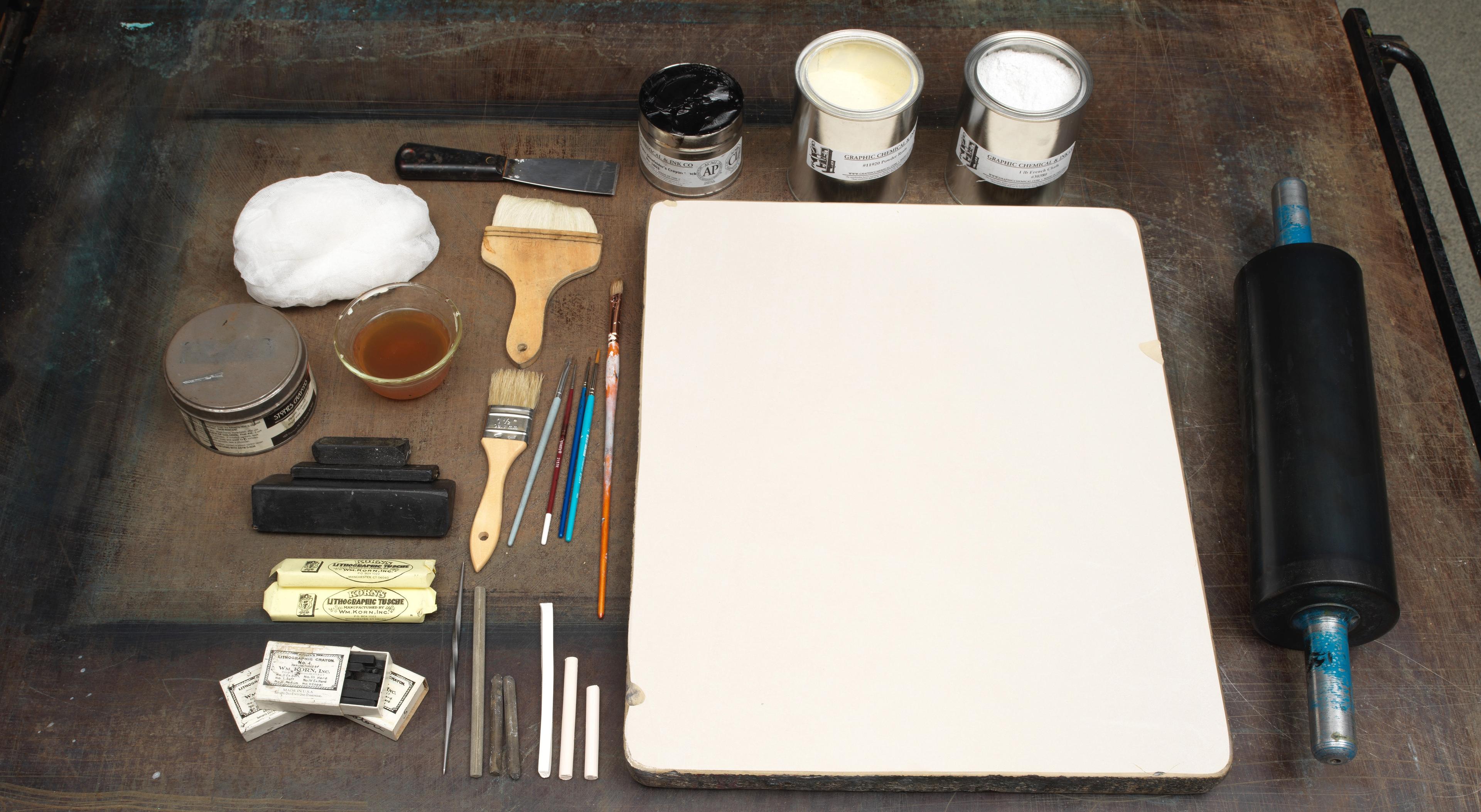 A tray of lithography tools, including a stone, crayon, sponge, and water