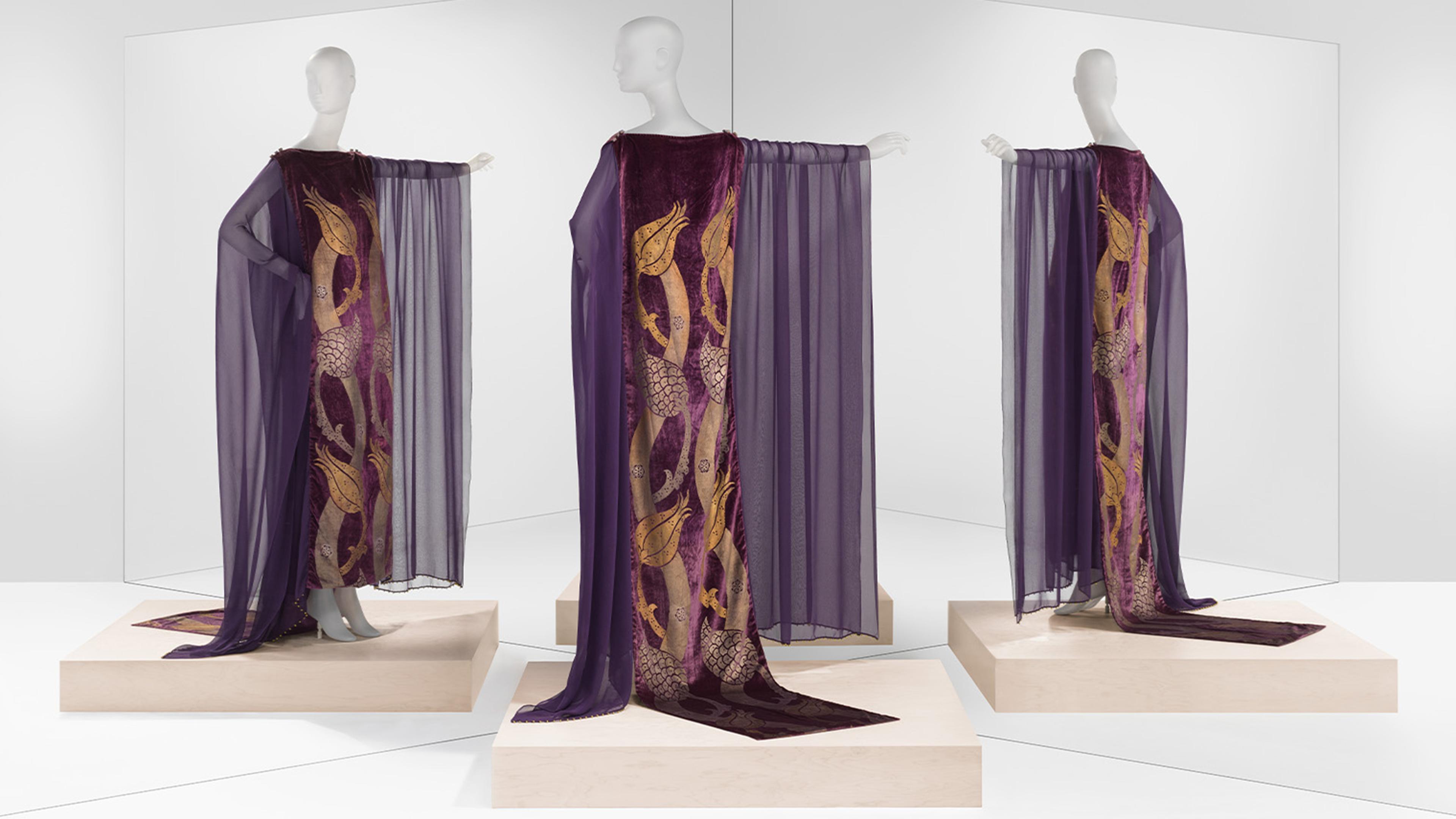 Three mannequins dressed in shoulder to floor purple gown and shawl.