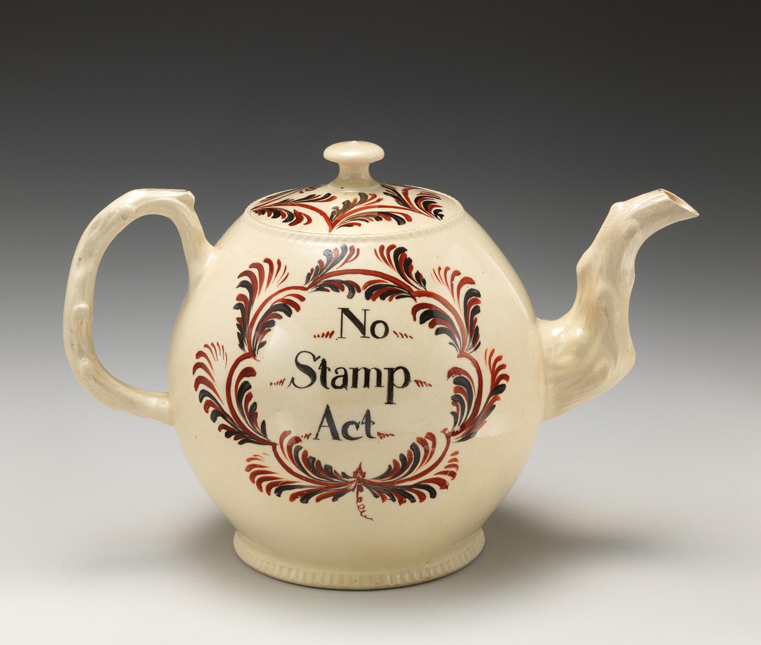 Cream-colored teapot with "No Stamp Act" in bold letters, surrounded by red and black leaf motifs.