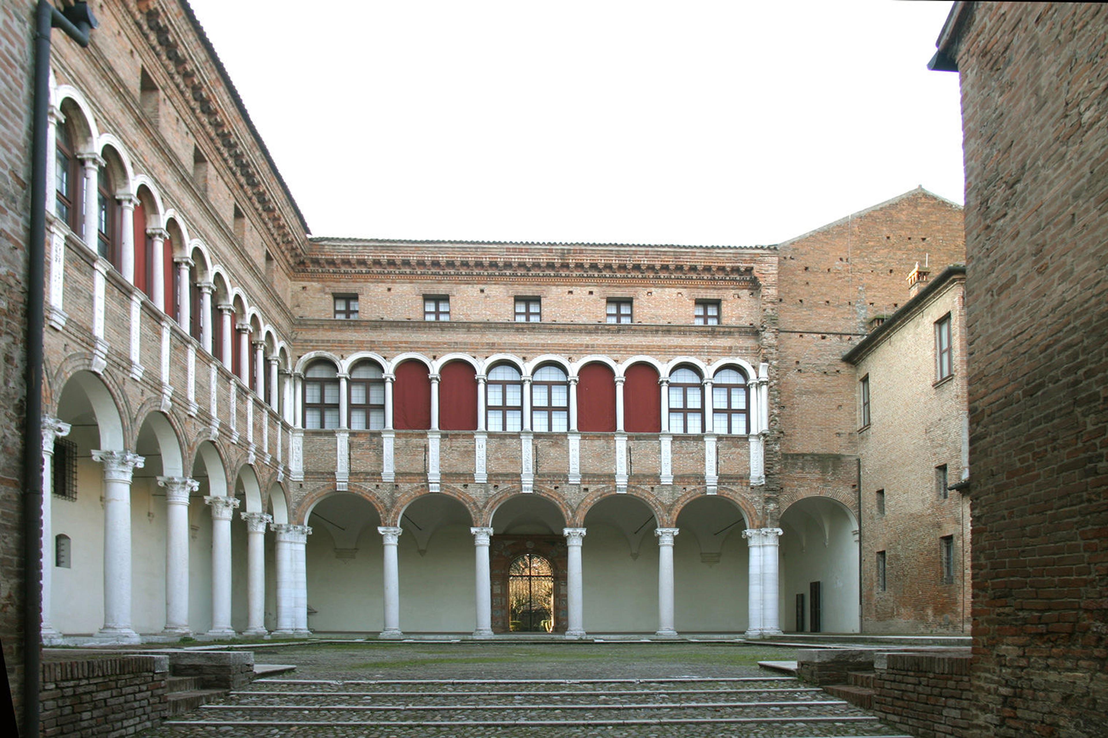 Image showing the entrance to the National Archaeological Museum in Ferrara. The stone facades open to a courtyard surrounded by white columns.