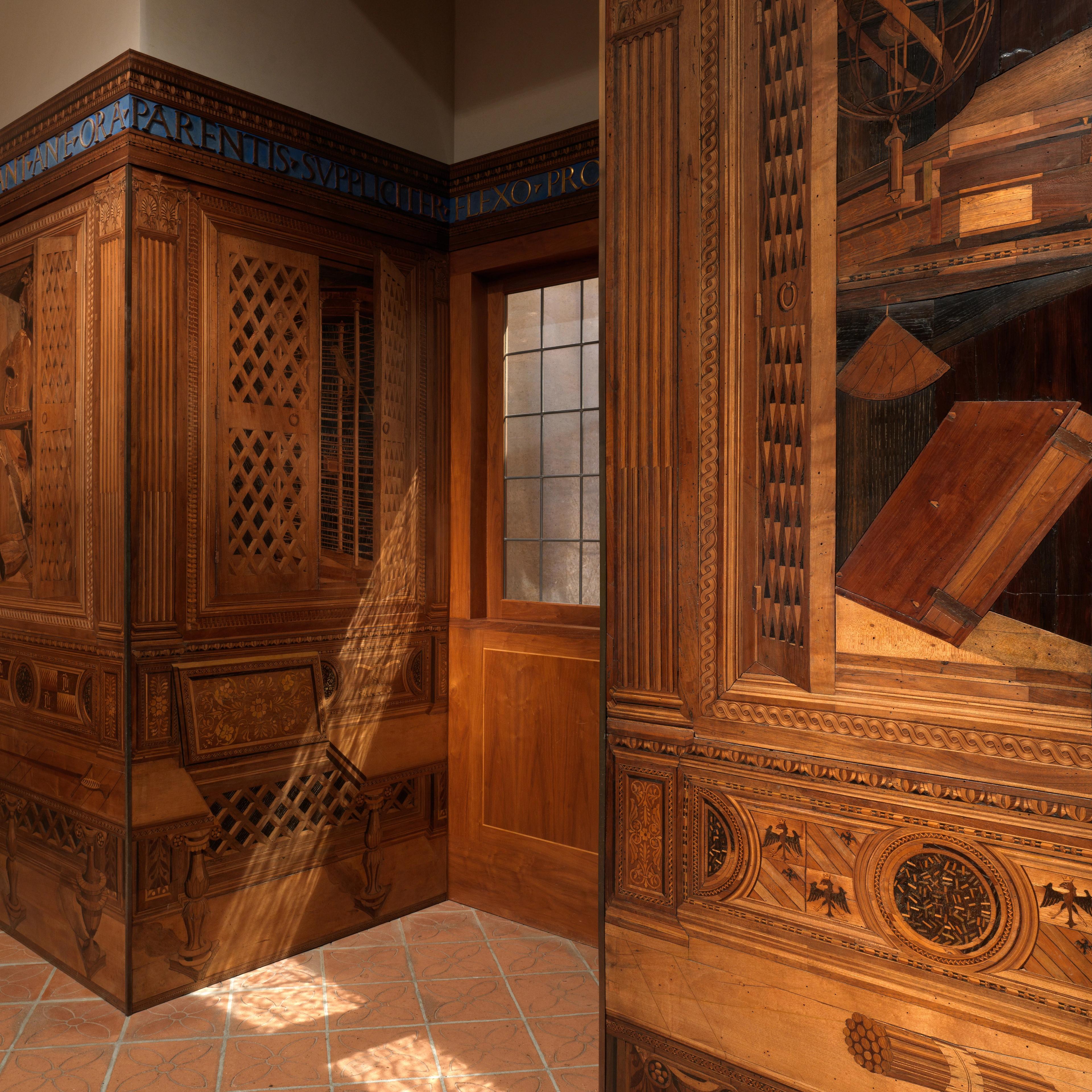Sun streaming into a Renaissance period room, with ornately decorated wood wall panels.