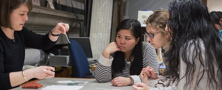 Teenage girls listening to a museum staff member in a conservation lab