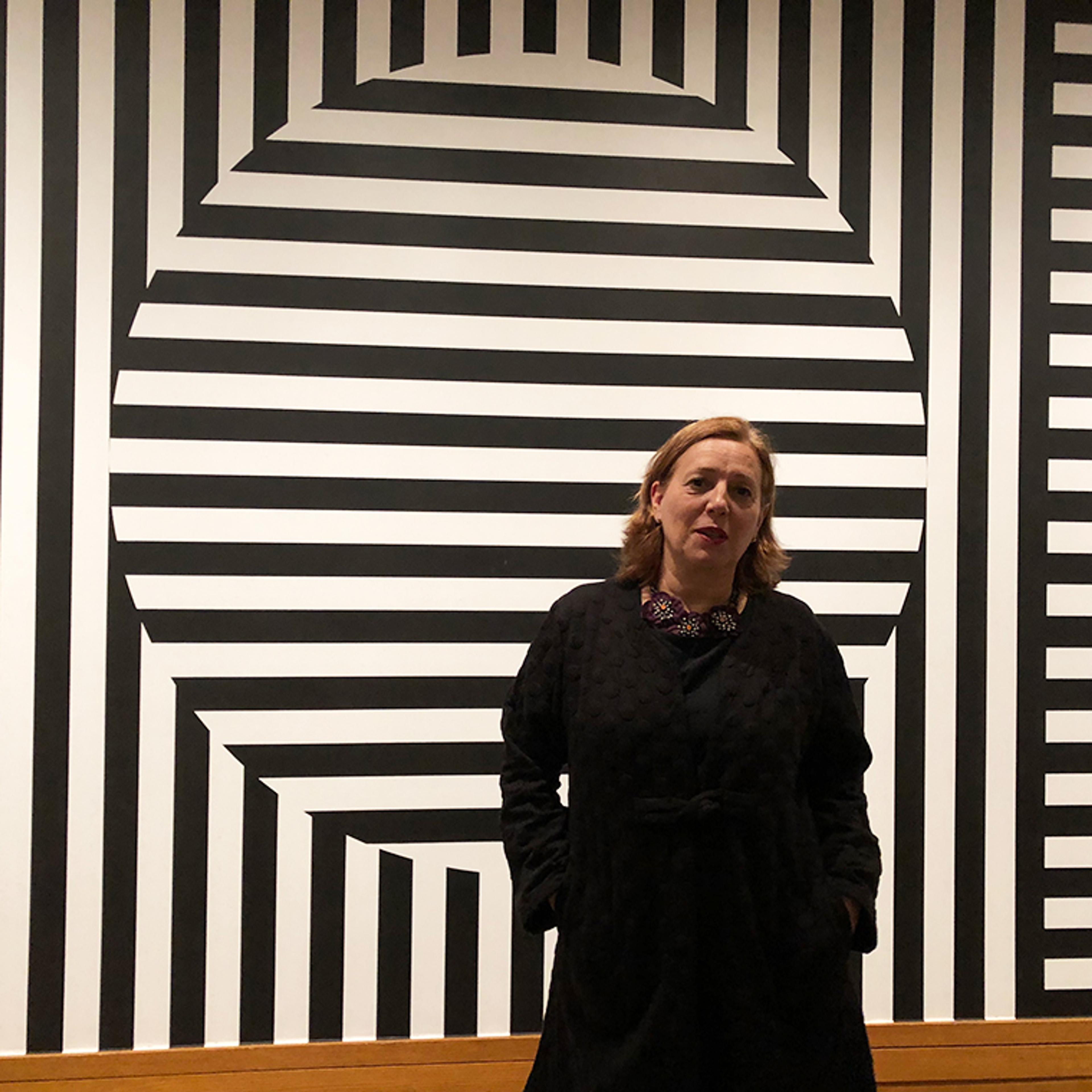 Woman in black standing in front of huge black and white striped wall painting by Sol Lewitt