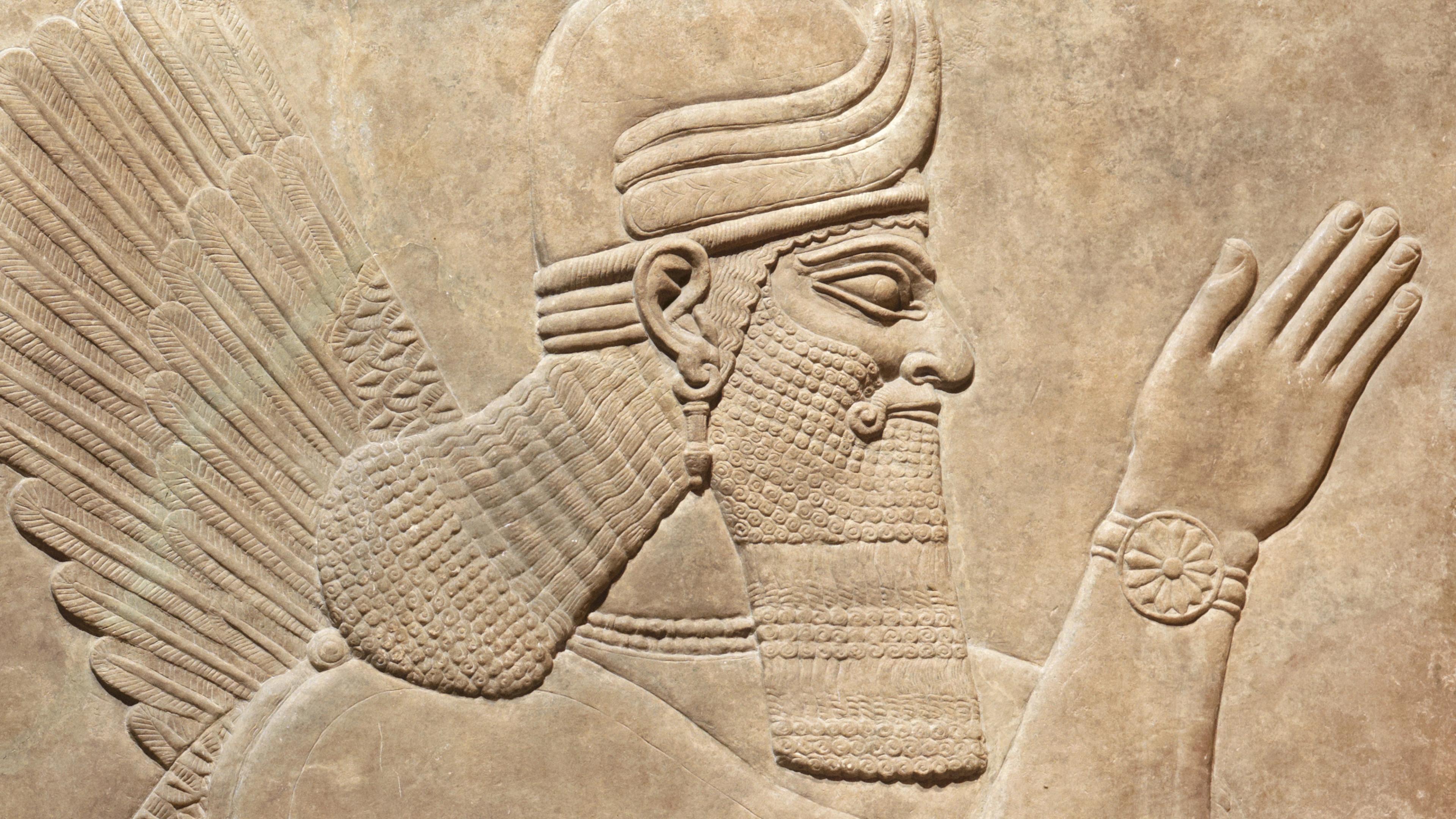 Relief of a winged figure with a long hair and beard gesturing towards the right.