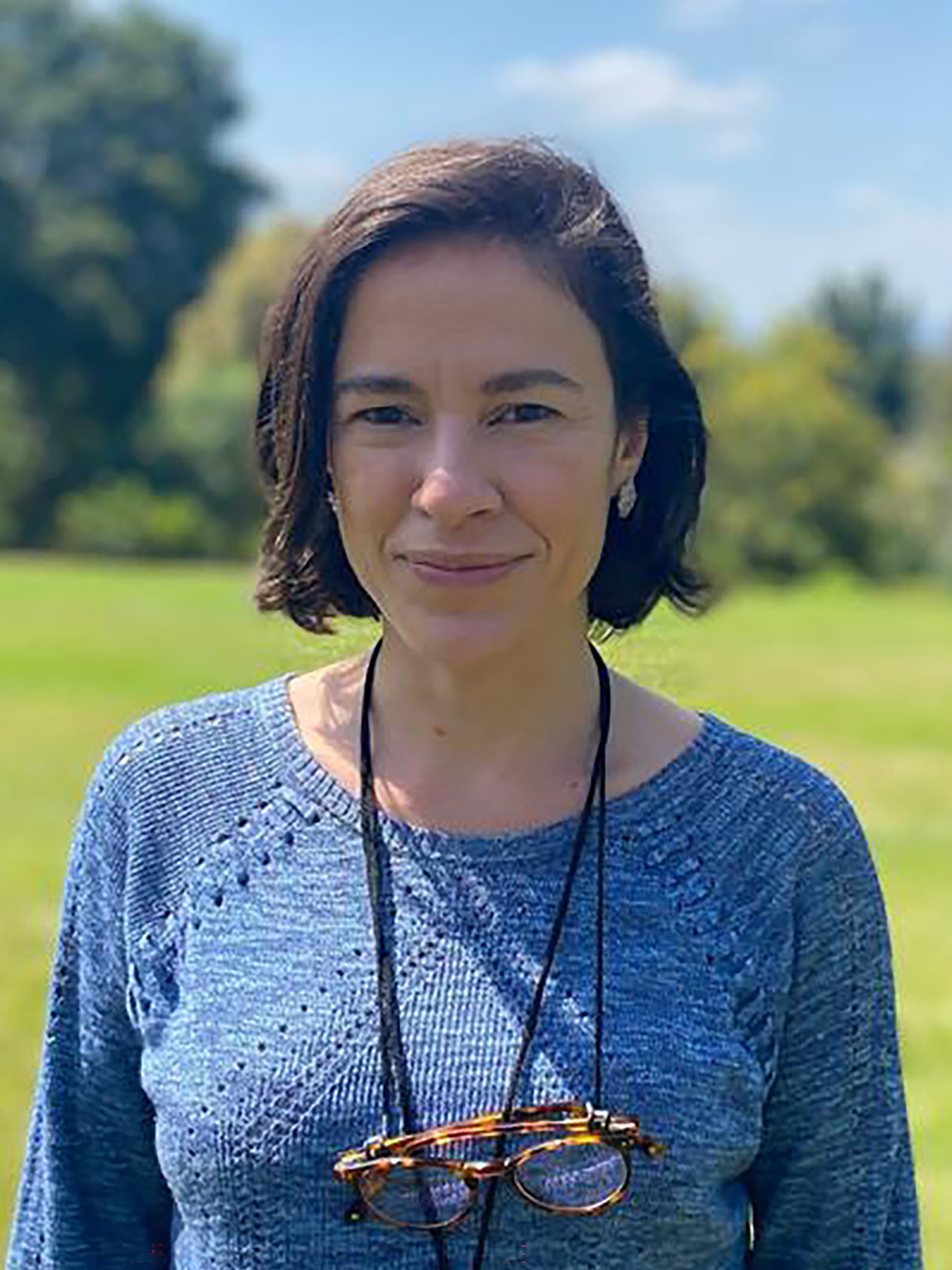 A woman in a blue sweater stands in a bright green field