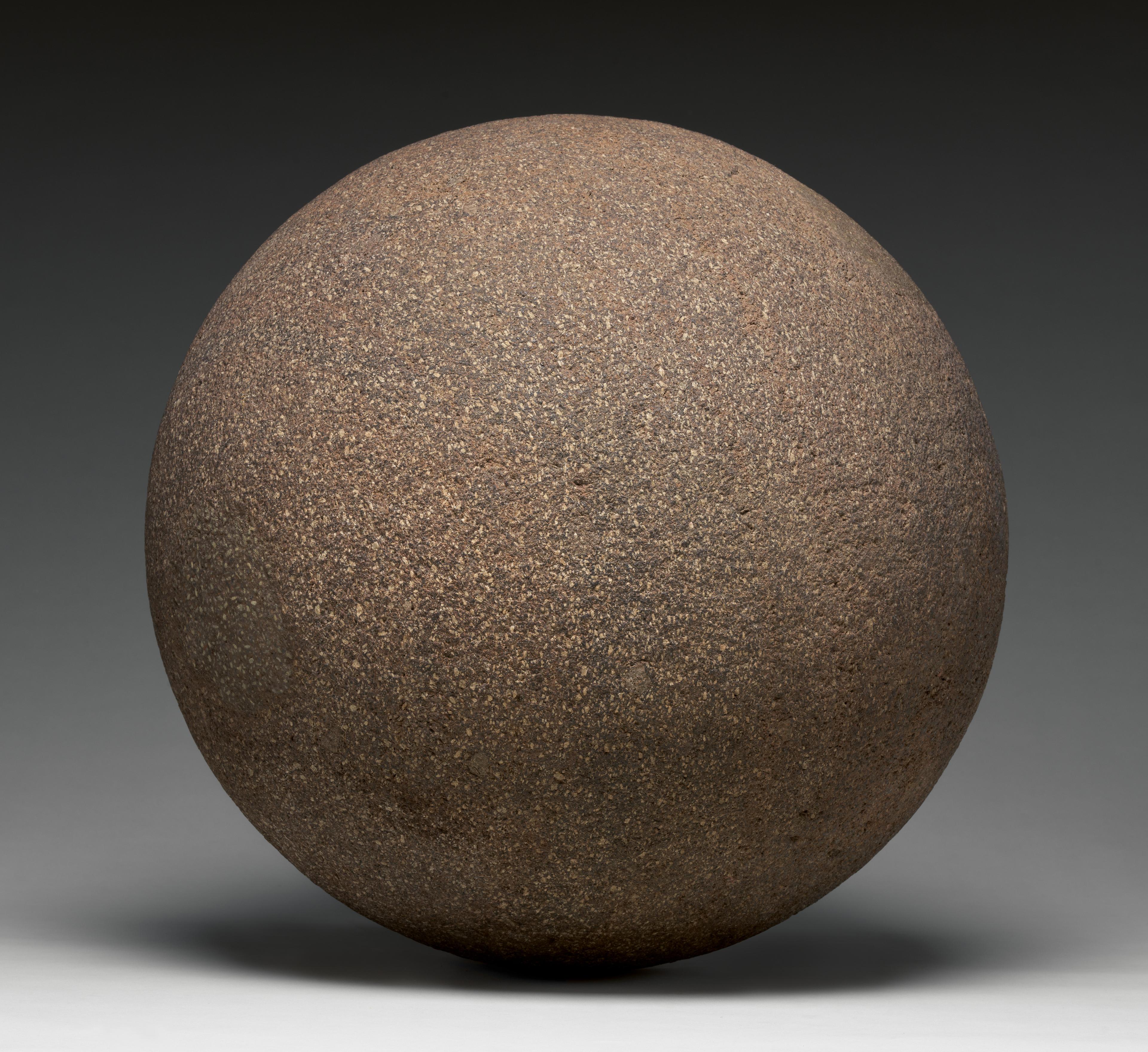 Photograph of a gray-brown stone sphere against a gray gradient background
