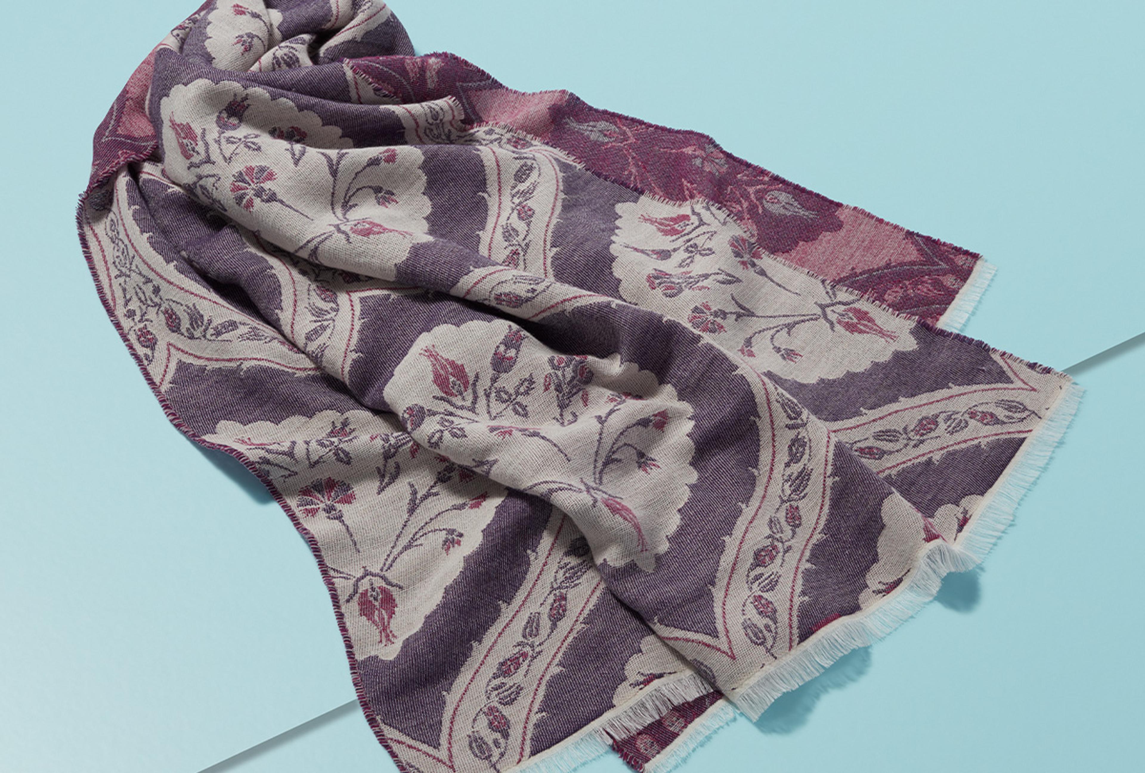 Scarf with a floral print photographed against a bright blue background.