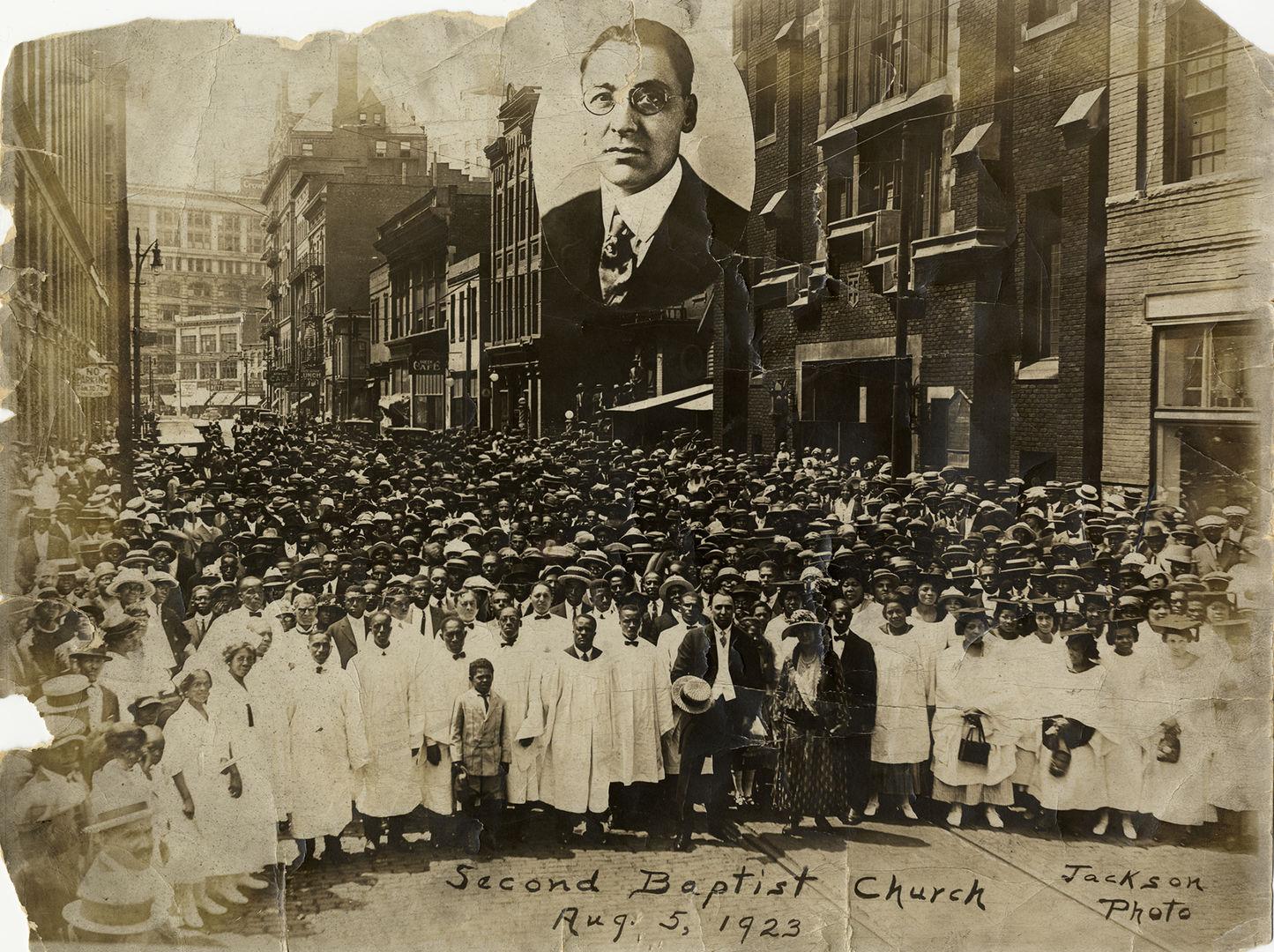 Group portrait of members of the Second Baptist Church in Detroit, Michigan. Congregation poses in front of church building located at 441 Monroe Street; commercial buildings in background. Inset portrait of the Reverend Robert L. Bradby. Handwritten on front: "Second Baptist Church, Aug. 5, 1923. Jackson photo." Stamped on back: "Harvey C. Jackson, photographer. Clifford 6054 M. 2614 Beaubien St., Detroit, Mich. Suitable frames for this photograph in stock or made to order."