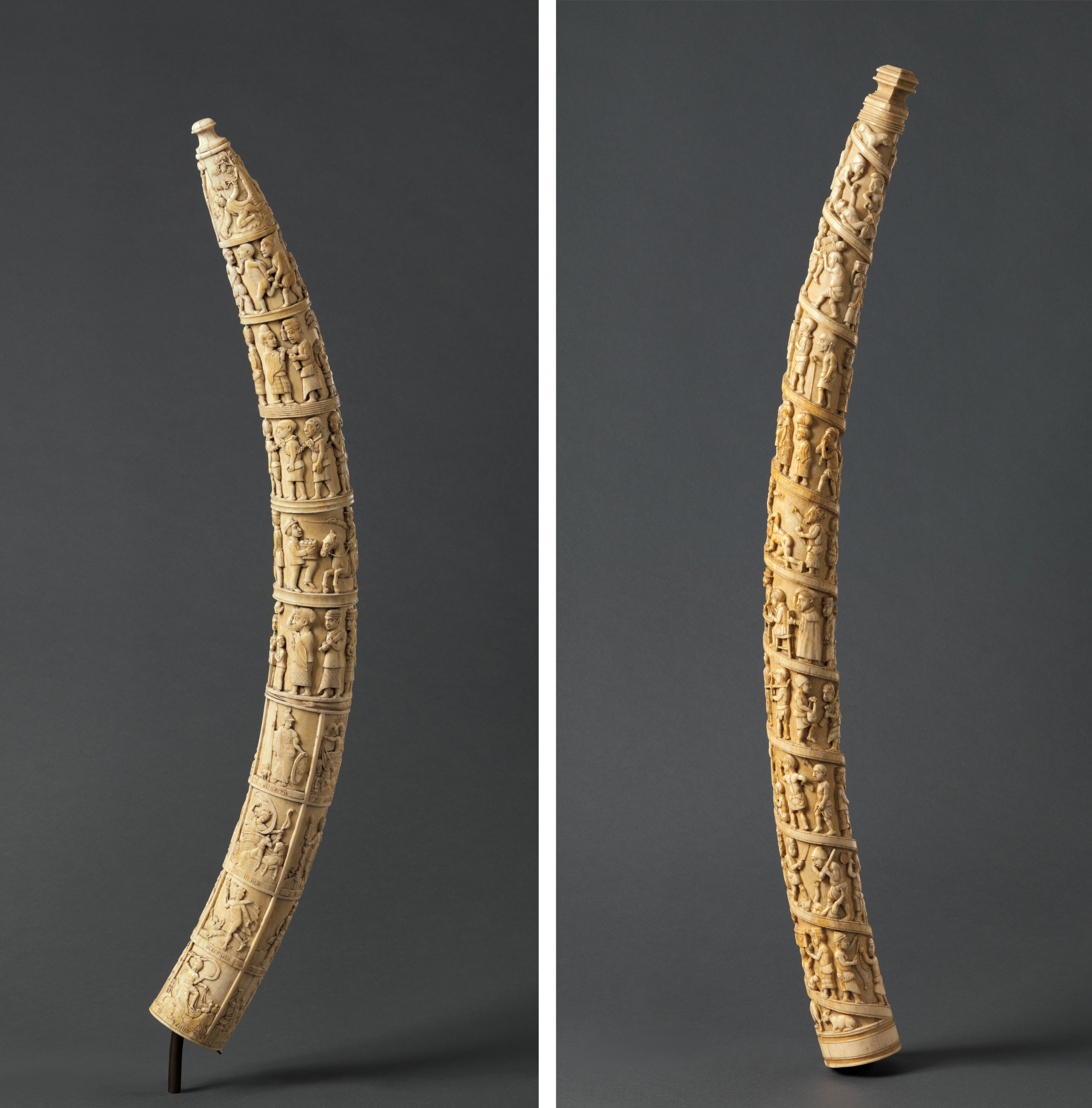Two ivory tusks with scenes carved in figurative relief filling the surface from top to bottom.