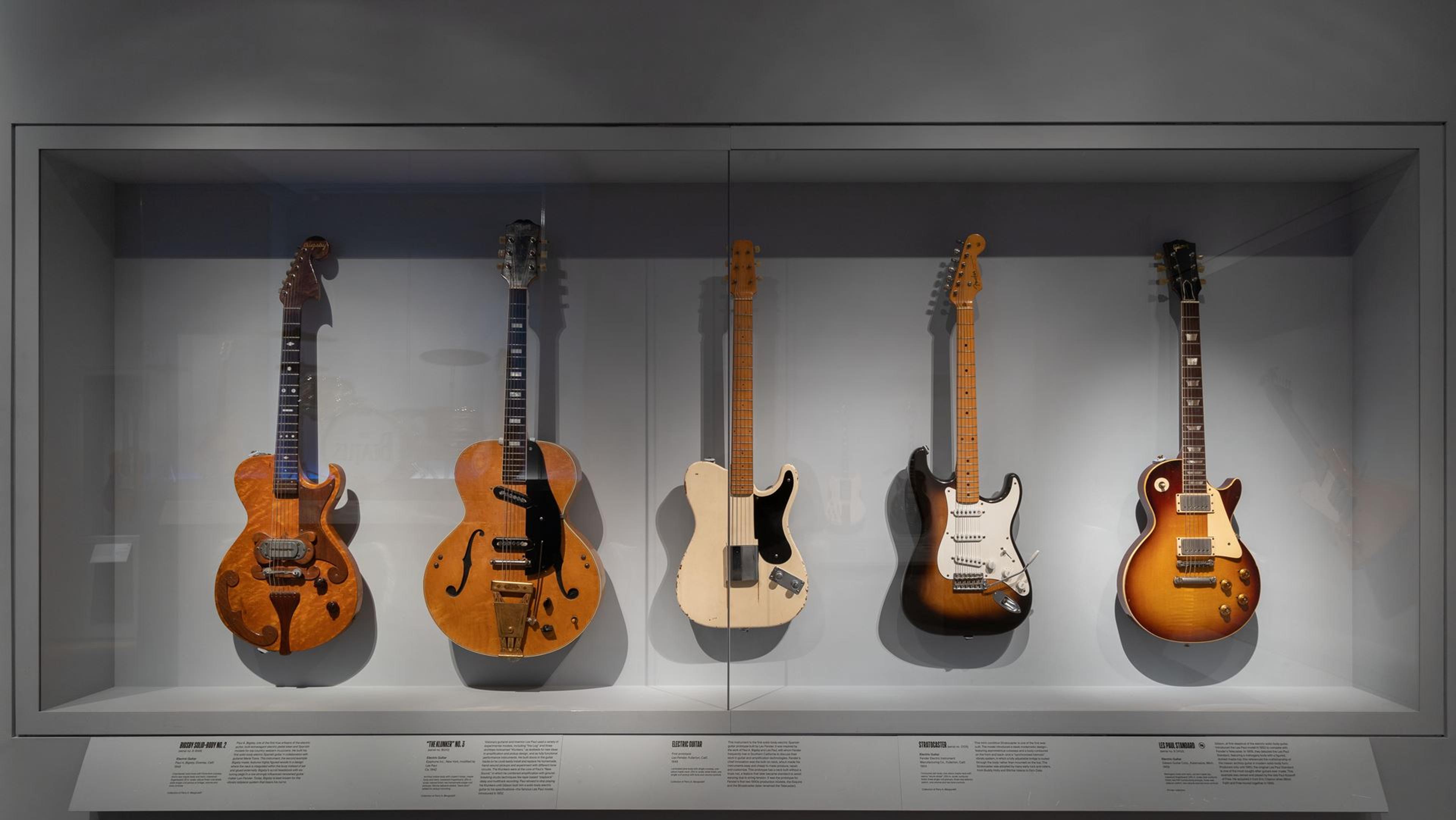Five guitars hanging on a wall in The Met's Musical Instruments galleries.