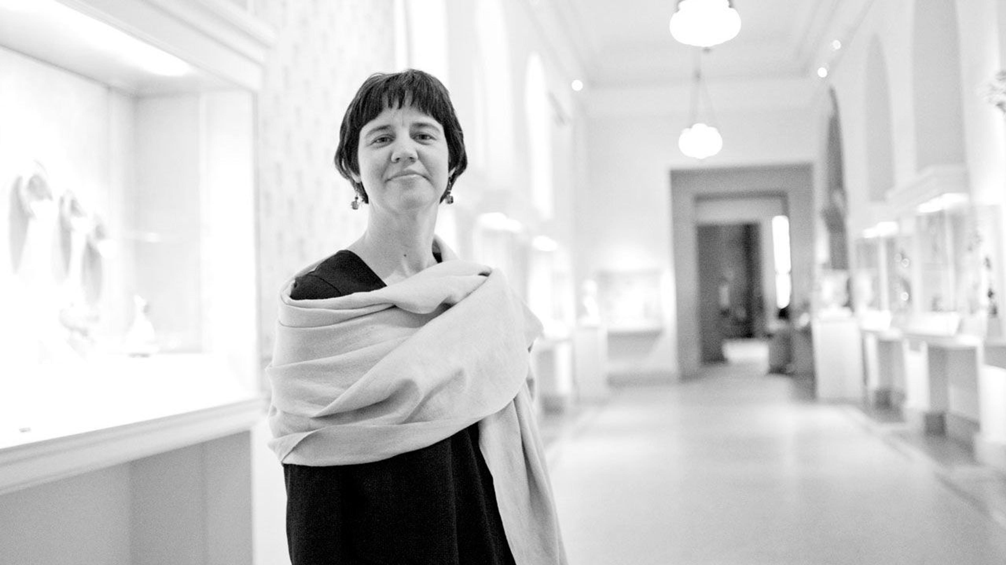 Black and white photograph of curator Melanie Holcomb standing in a gallery at The Met