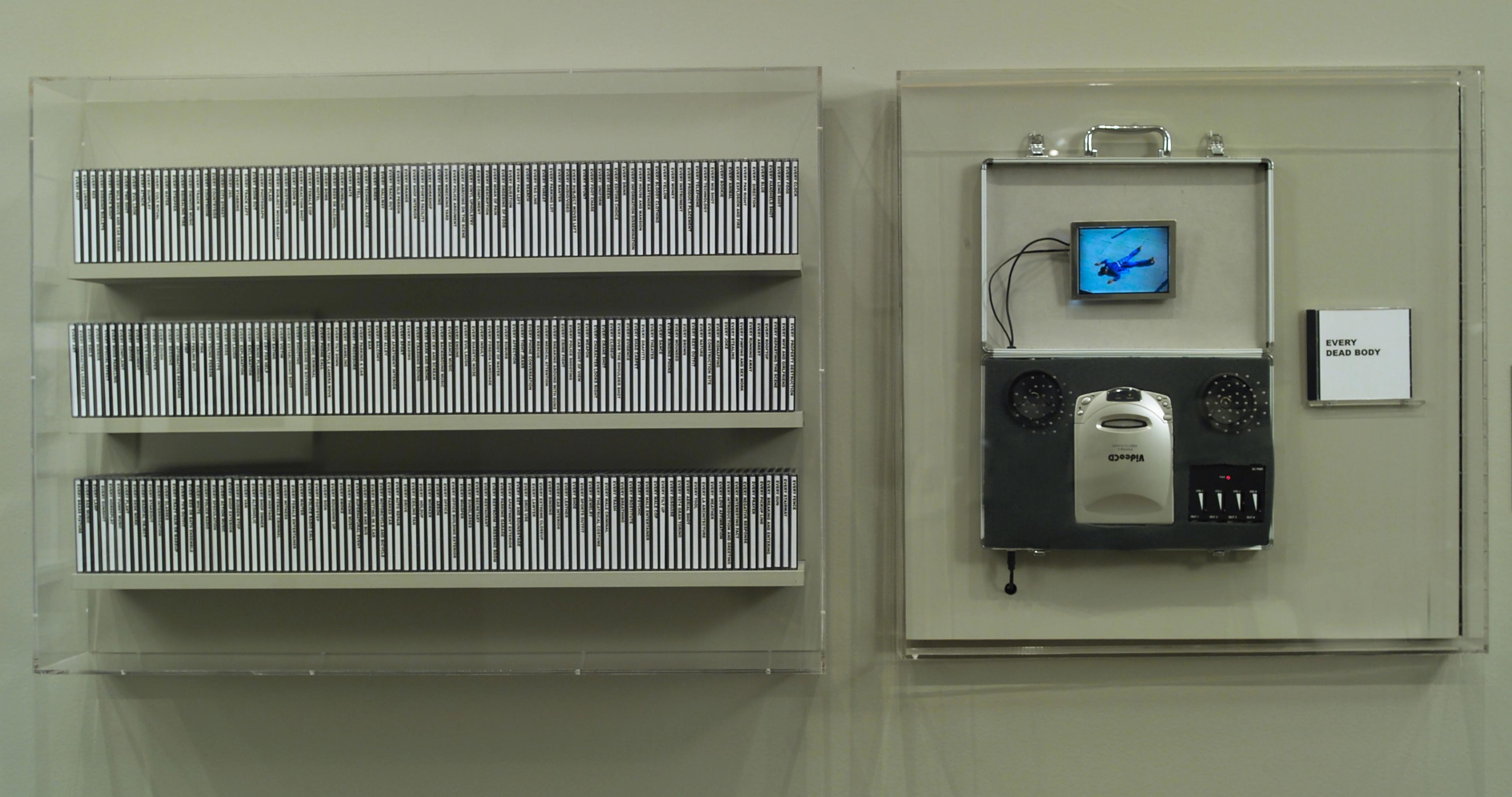 At left, three wall-mounted shelves of CDs. To the right of the shelves, a video CD player with exposed wires, attaching to a small screen showing a figure in blue lying face down. To the right of the player is a small CD with cover art that reads "EVERY DEAD BODY."