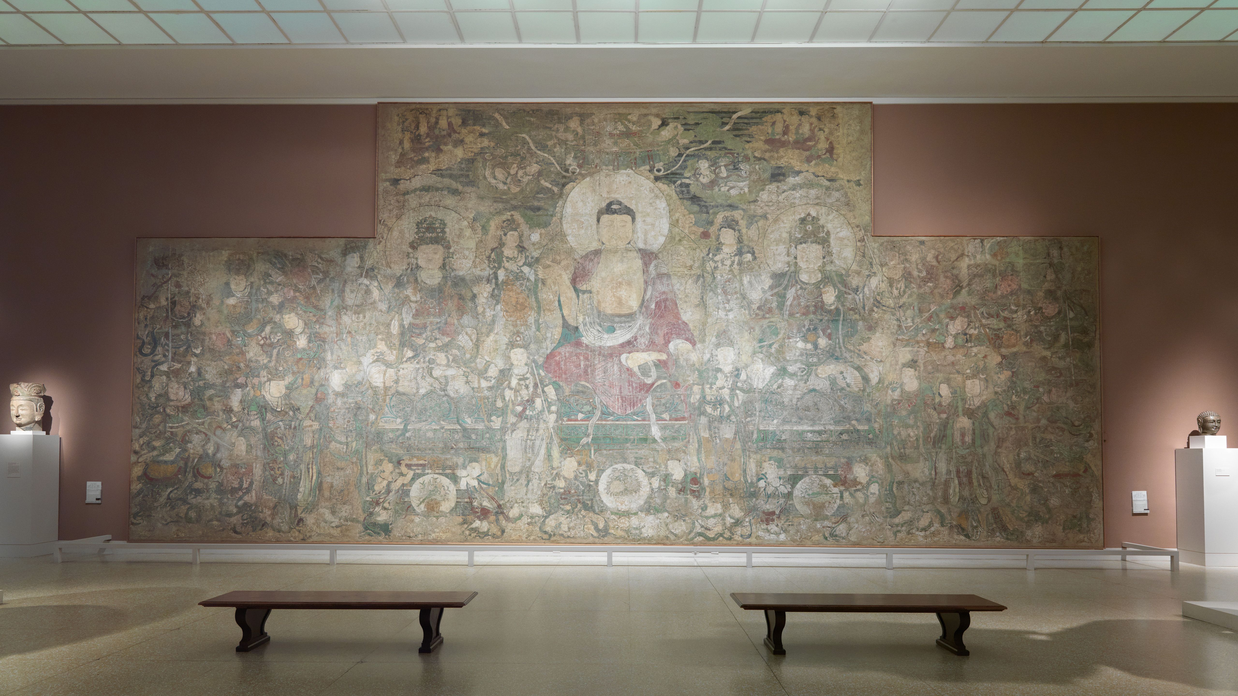 In-gallery view of a large, faded mural of the Buddha.
