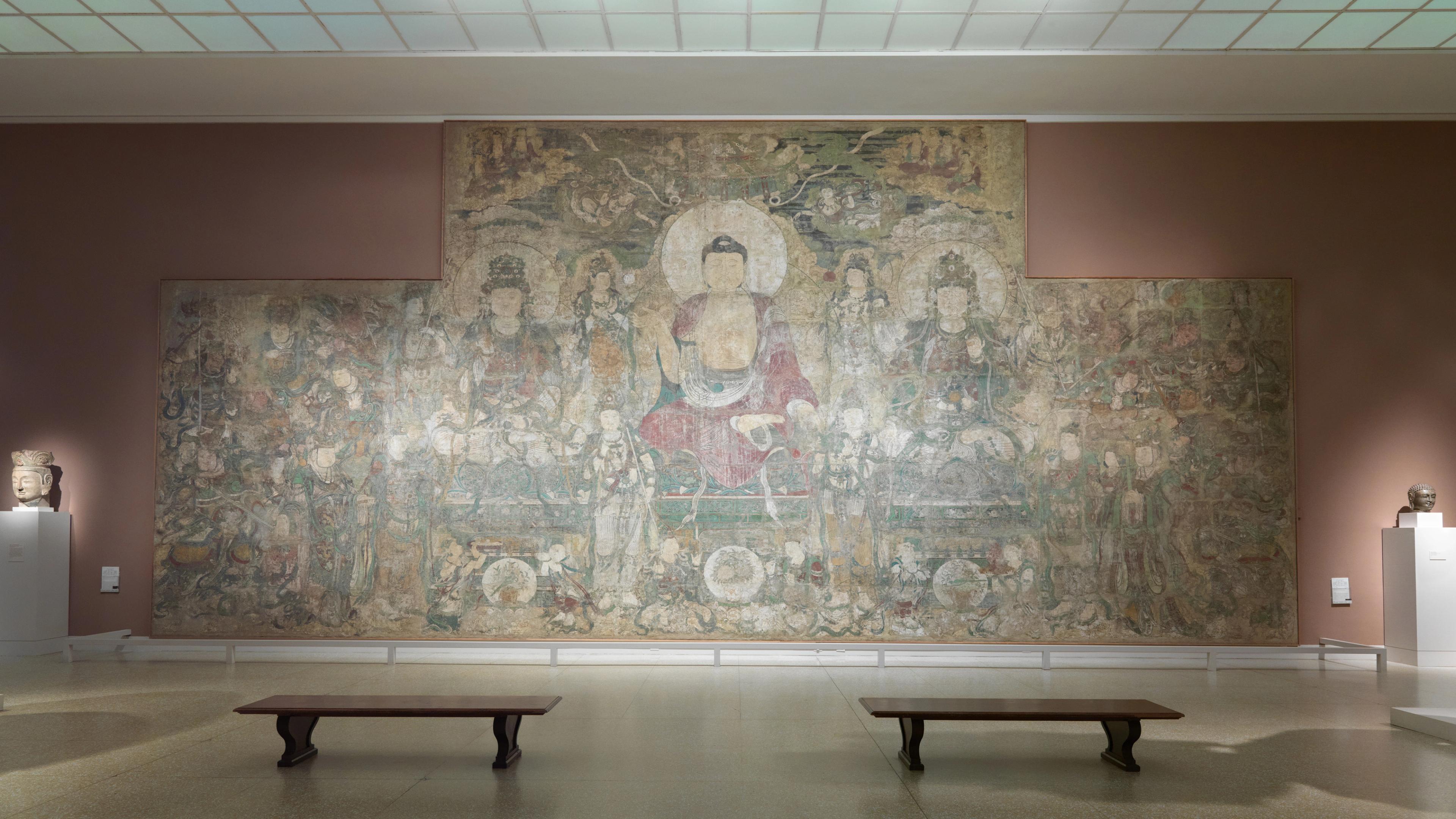In-gallery view of a large, faded mural of the Buddha.