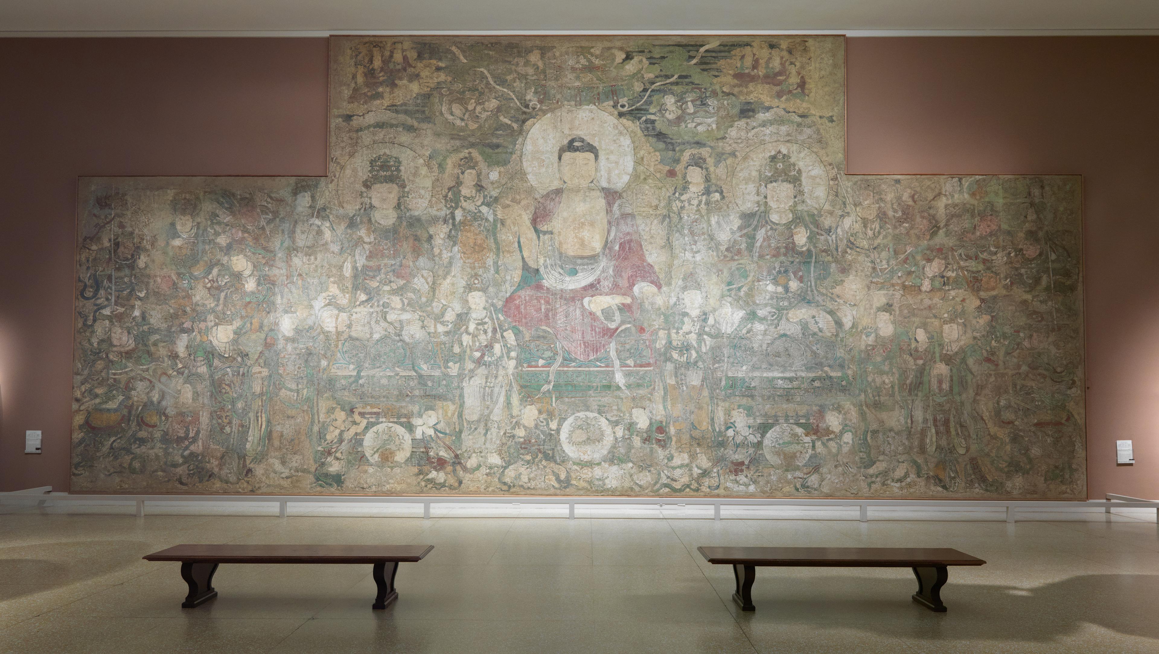 In-gallery view of a large, faded mural of the Buddha.