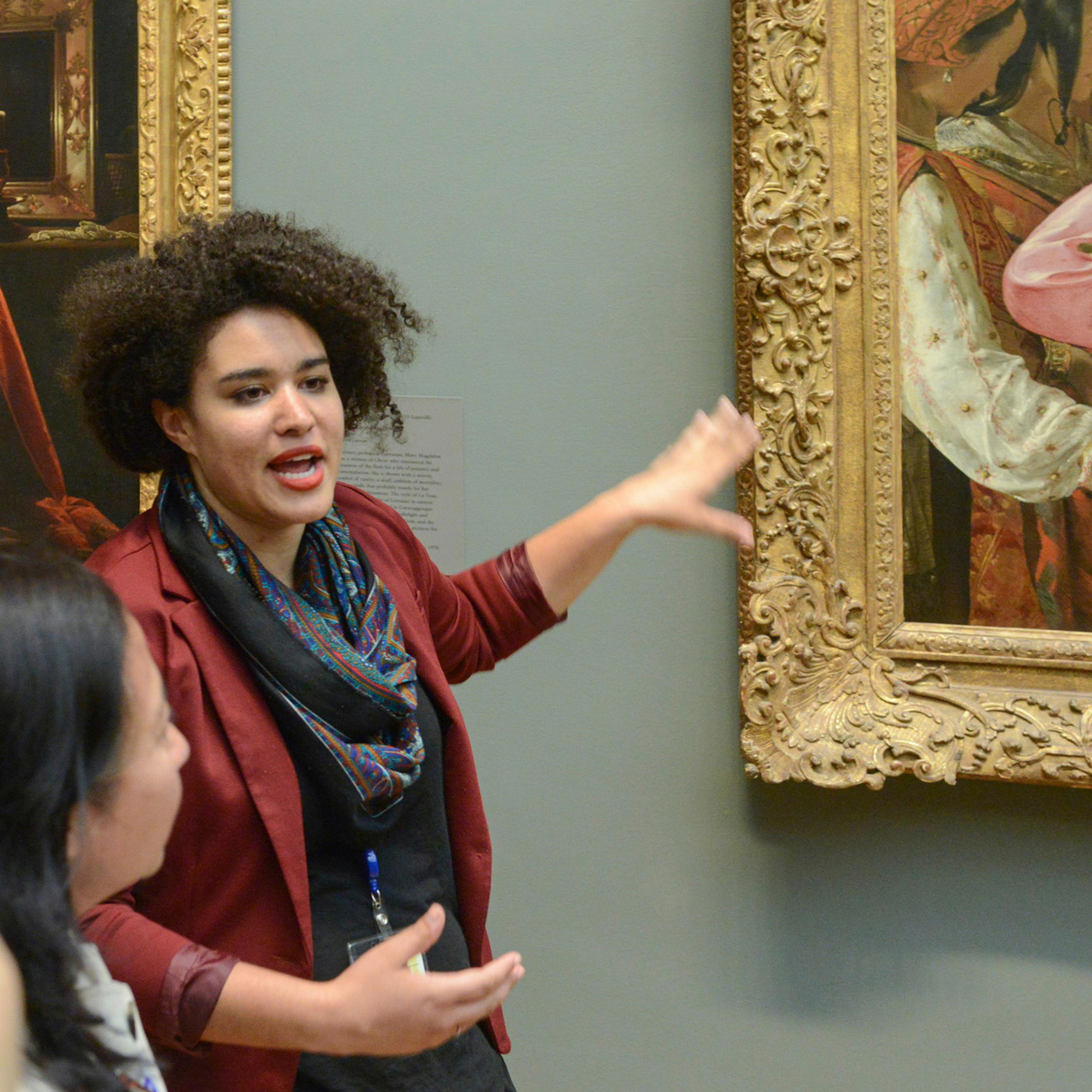Tour Guide pointing to a painting and explaining the context to a group of visitors.